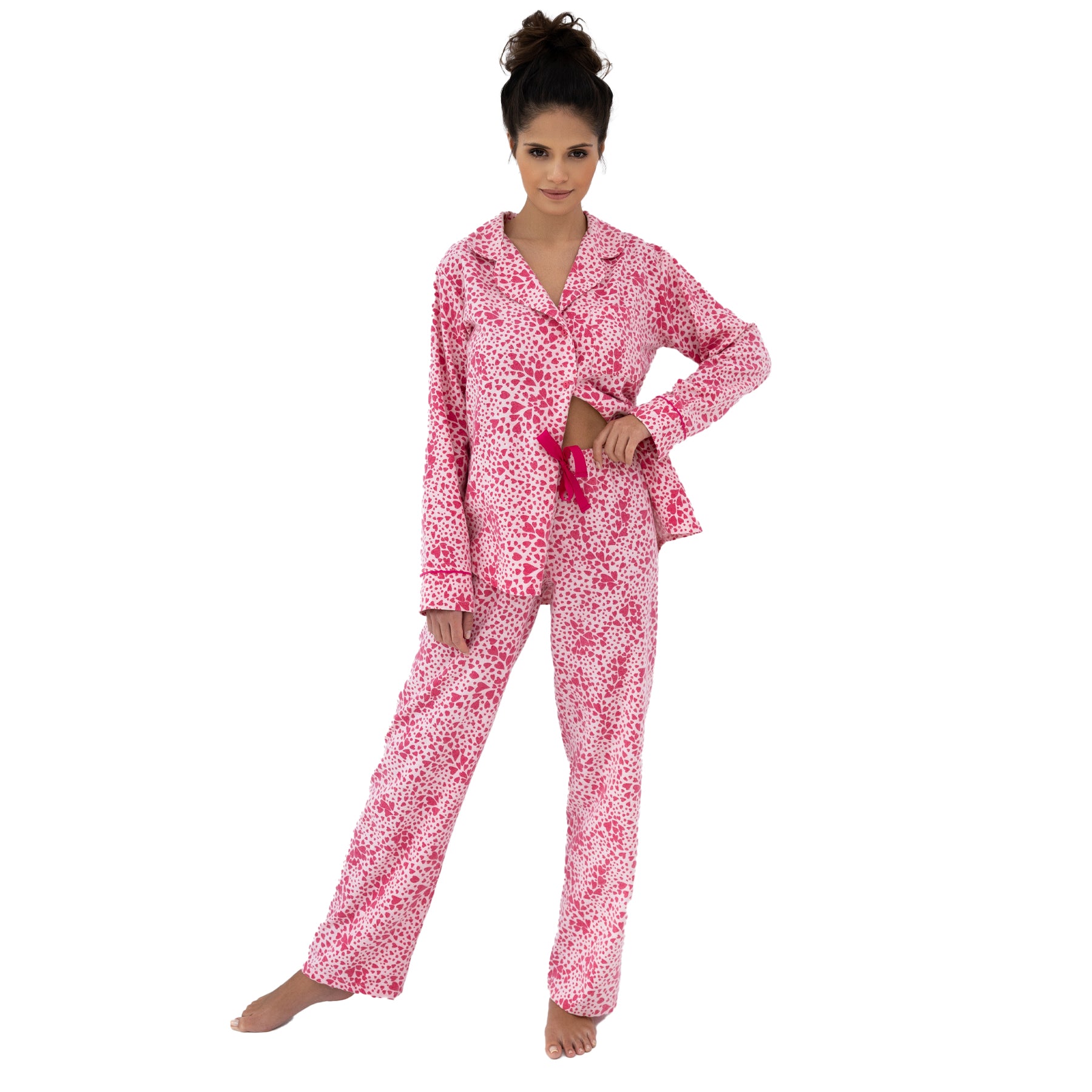 Full-length view of woman standing in pink heart-pattern pyjama set, showcasing relaxed silhouette and comfortable design.