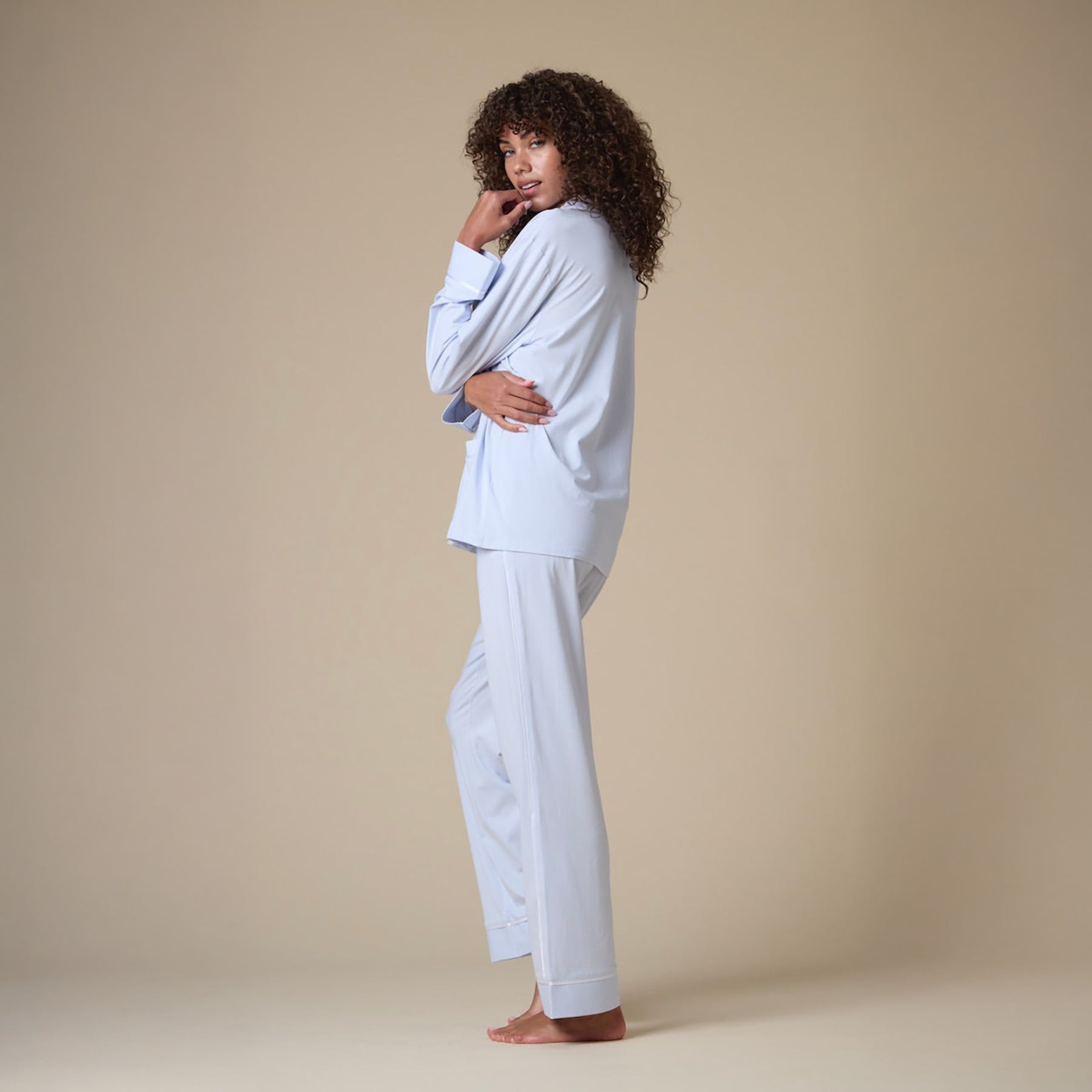 Classic cotton button up pyjama set in baby blue with contrast white piping. Side view on model.