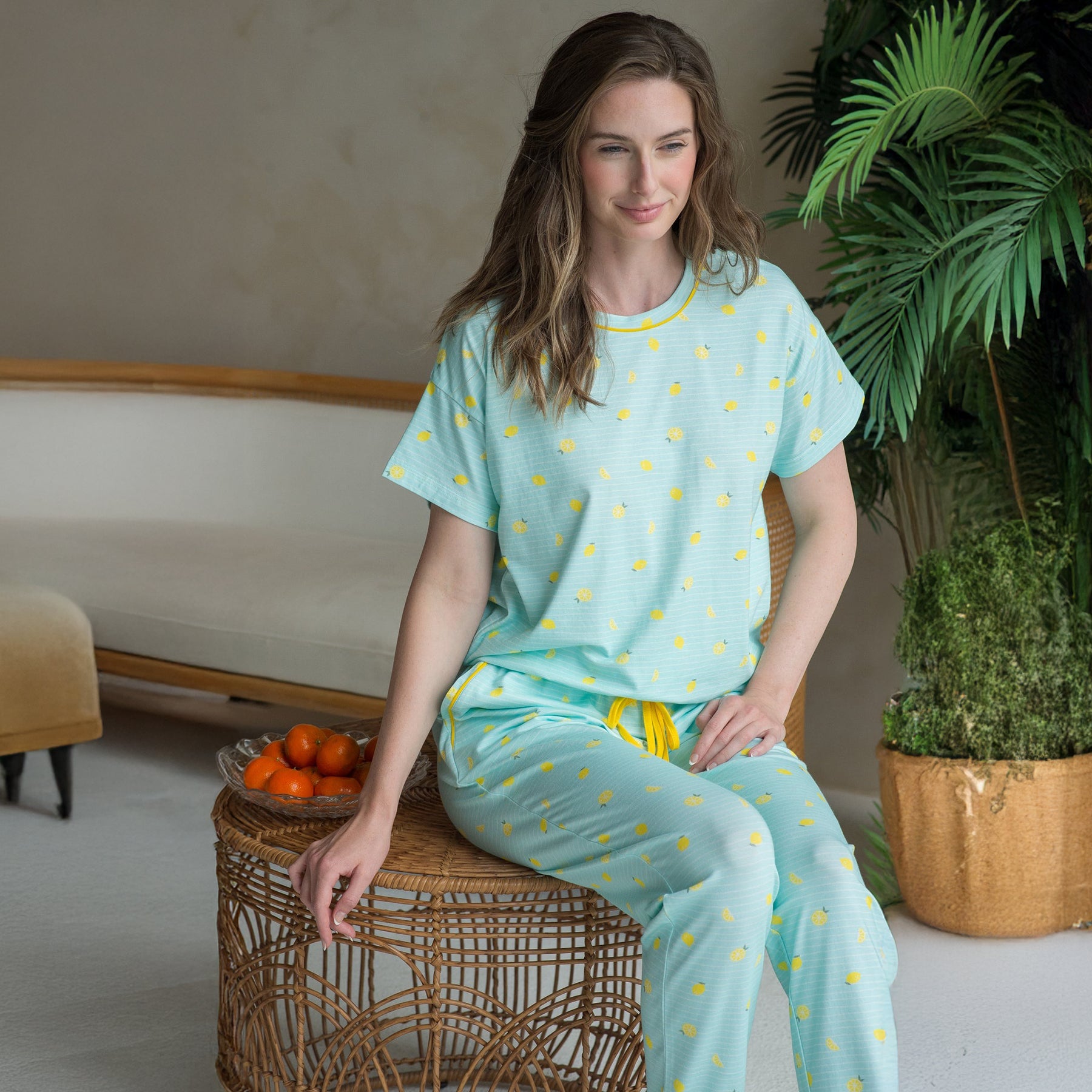 Model seated in aqua lemon print pyjama set - soft cotton short sleeve top and jogger pants with yellow drawstring.