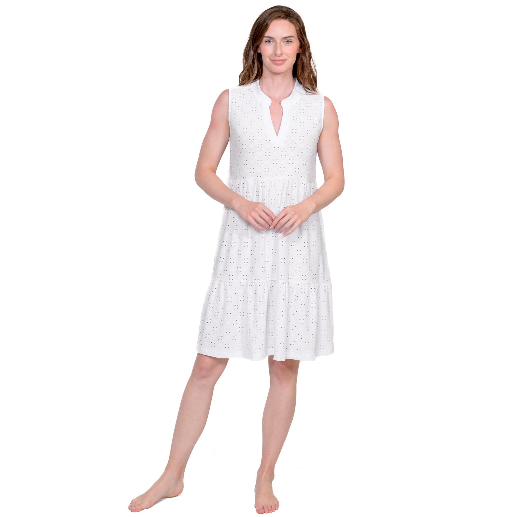 Front view of sleeveless white cotton dress with eyelet detailing and tiered skirt - model standing.