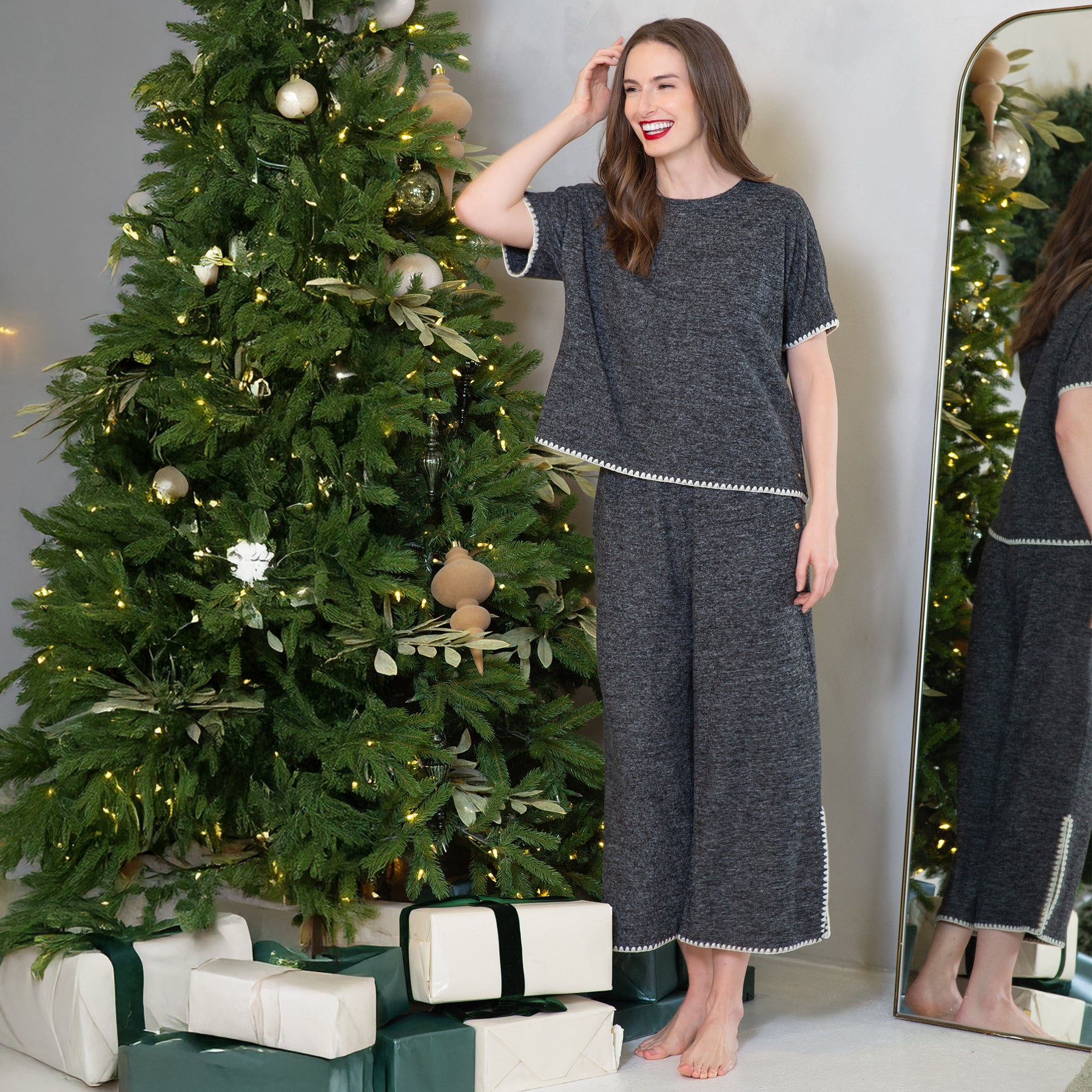 Lifestyle image – woman standing by Christmas tree wearing LatteLove Short Sleeve Blanket Stitch Lounge Set in Black Mix.