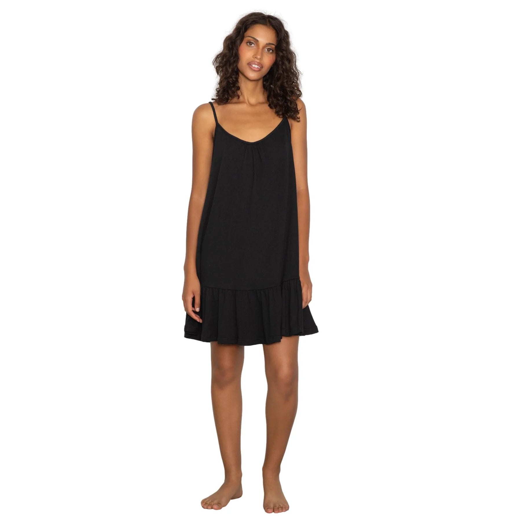 Black sleeveless slip dress with thin straps and ruffle hem, relaxed fit silhouette, front view on model
