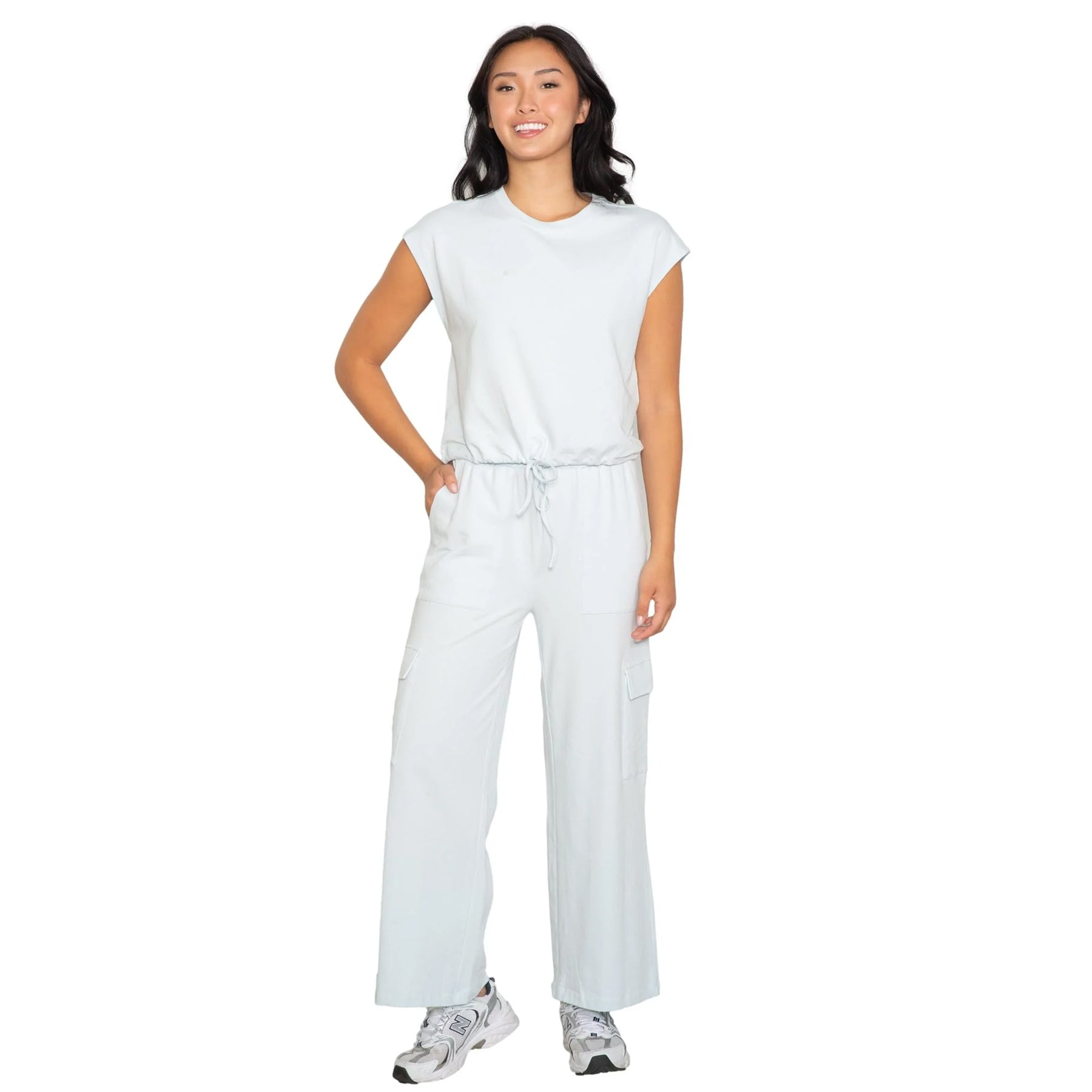 Light blue sleeveless jumpsuit with drawstring waist and wide-leg pants, styled with sneakers, front view