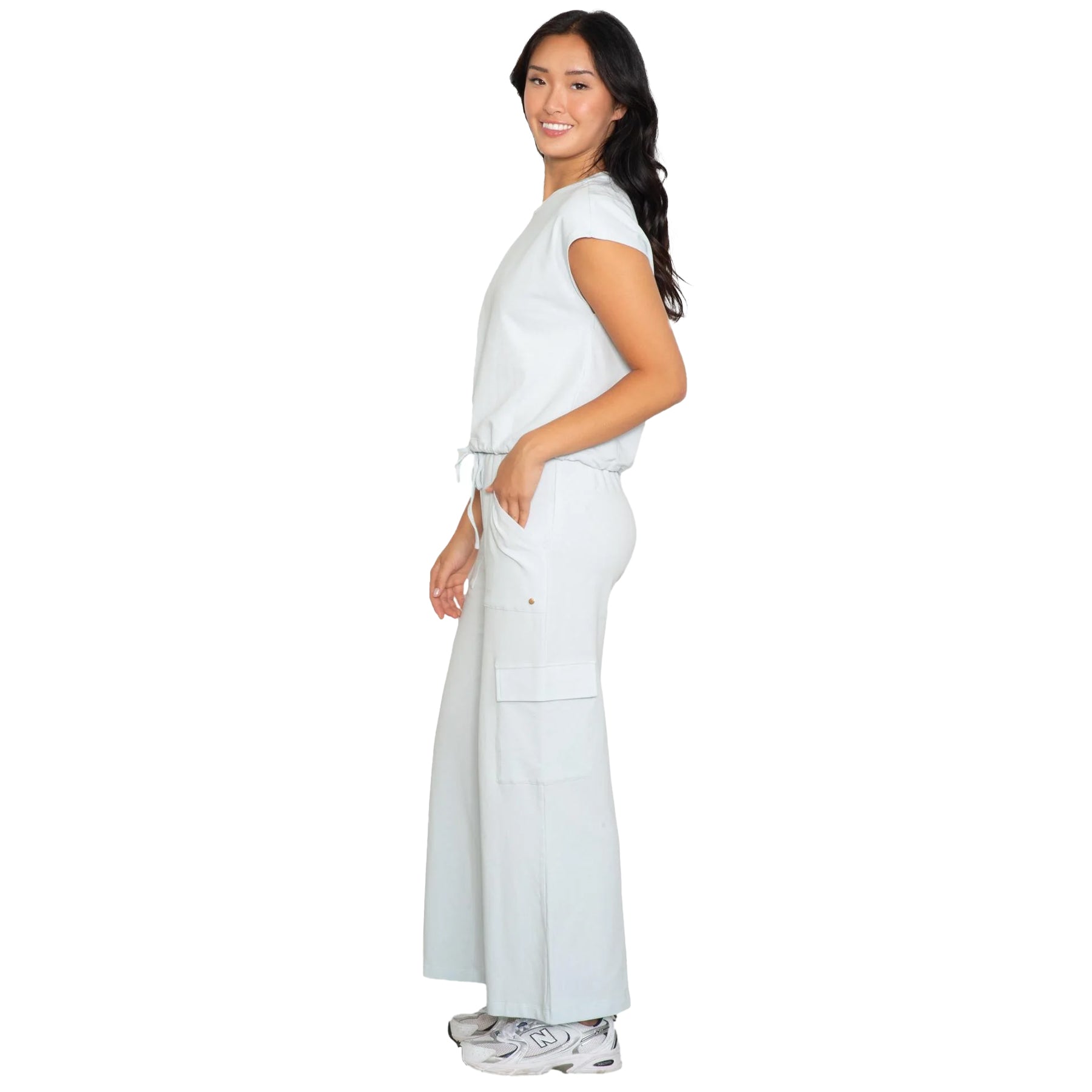 Soft blue relaxed-fit jumpsuit with cap sleeves, adjustable waist tie, and side cargo pockets, side view