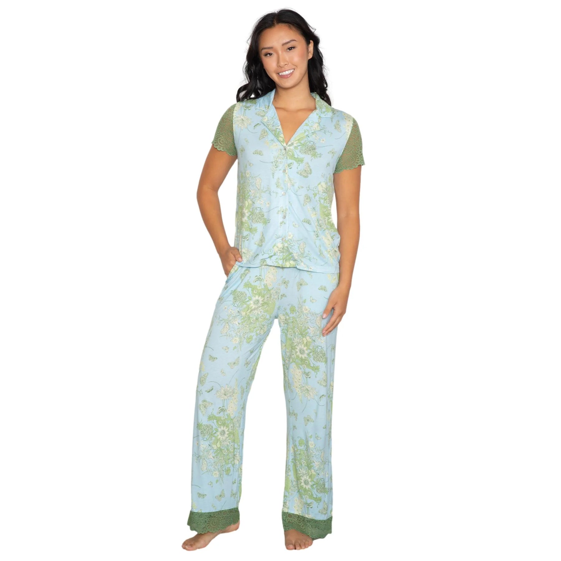 Woman wearing a light blue floral print pajama set with green lace trim sleeves and hem, short sleeve top and relaxed fit pants on white background