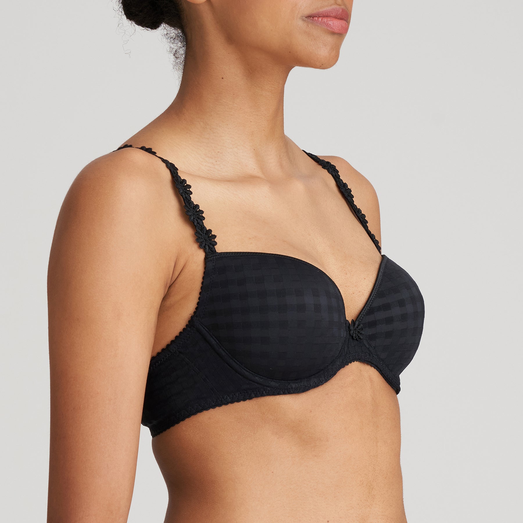 Padded plunge bra in black with checkerboard print and embroidered daisy straps. Side view on model. 