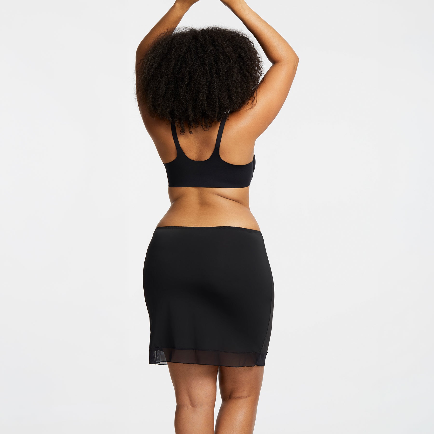 Montelle Intimates 9502 18-inch half slip above knee in Black colour with sleek smoothing fit and sheer hem detail, back view on curvy model.