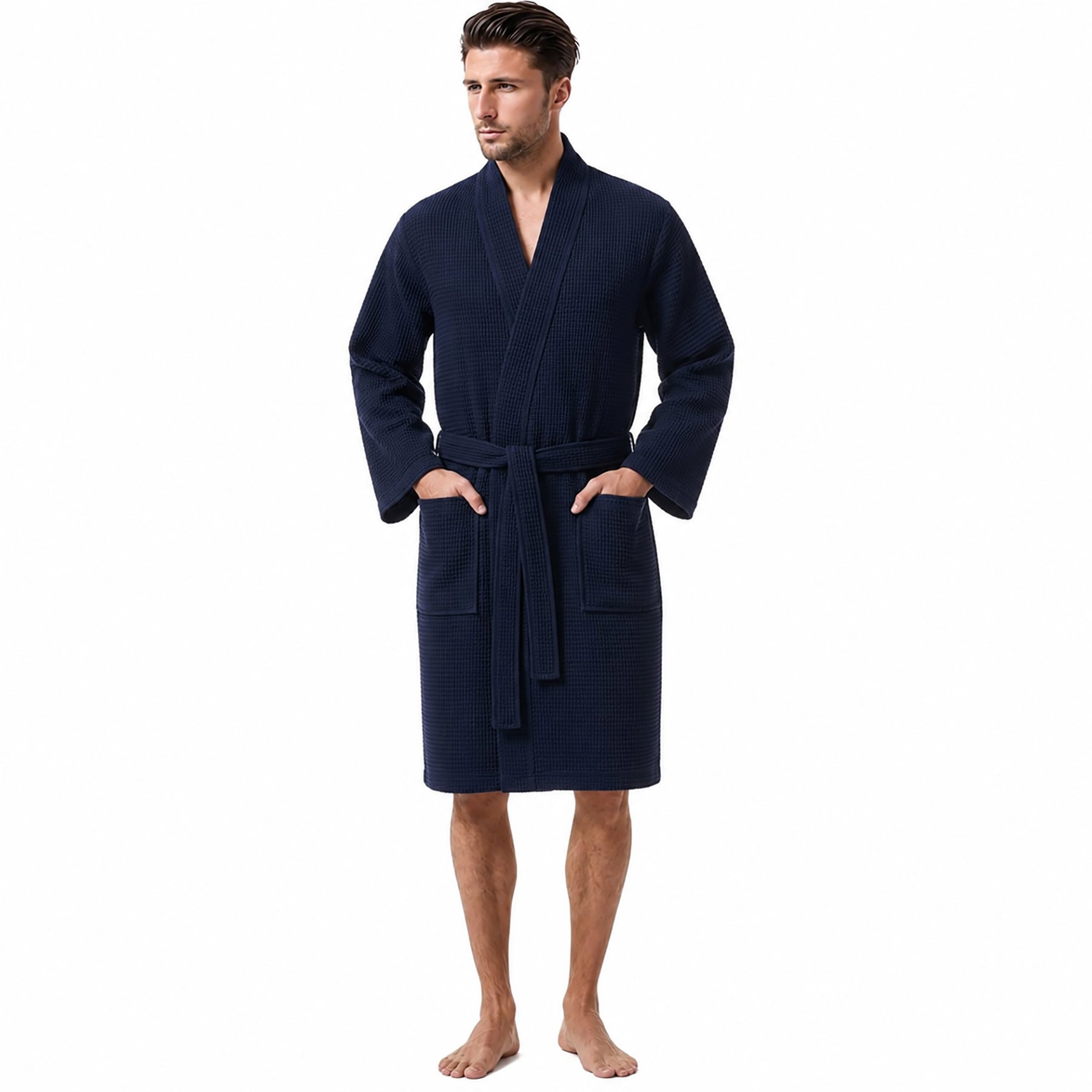 Morgenstern long unisex waffle robe in navy – 100% cotton spa robe with belt and front pockets. Worn by man facing front with hands in pockets.