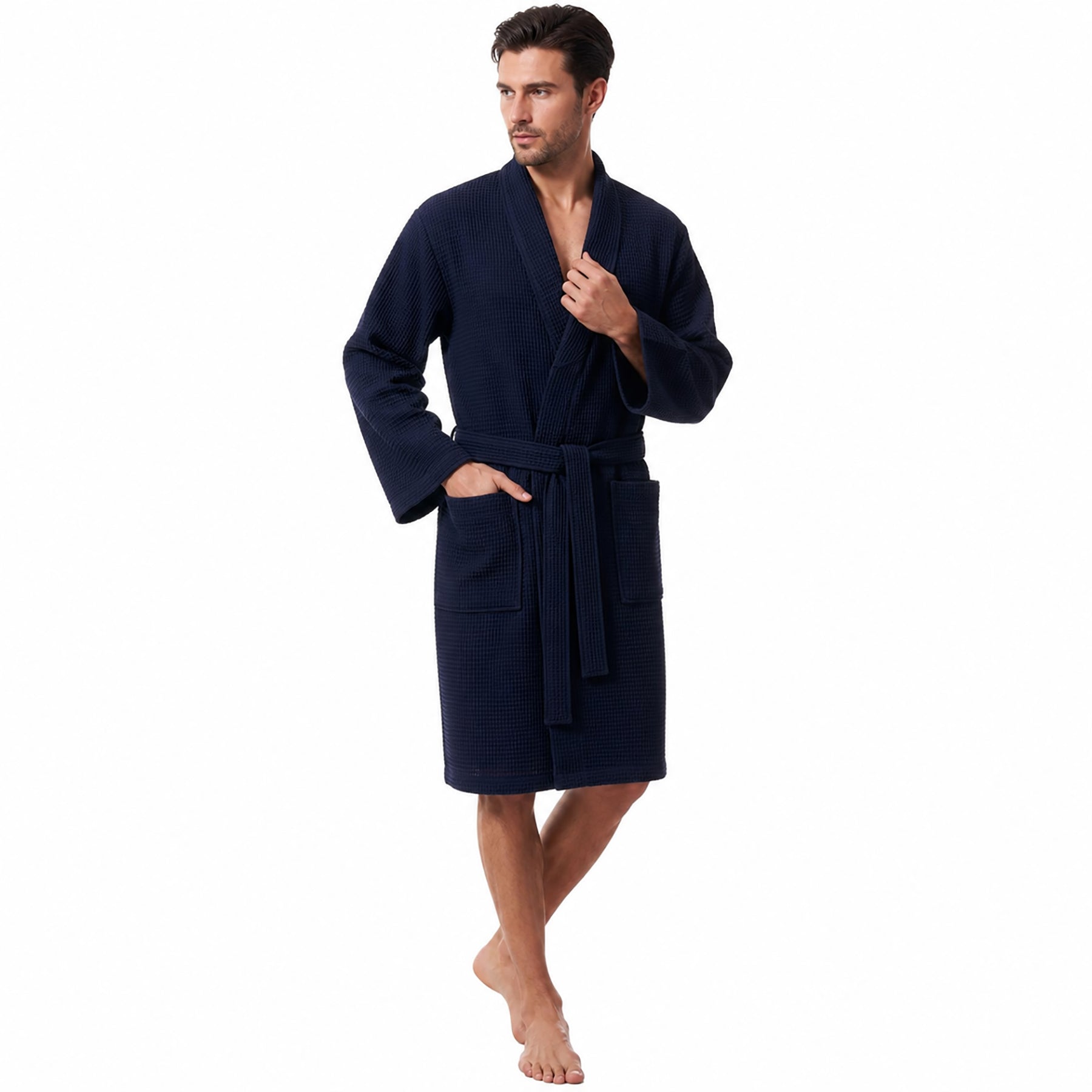 Morgenstern long unisex waffle robe in navy – 100% cotton spa robe with belt and front pockets. Worn by man facing front angled with hand in pocket.