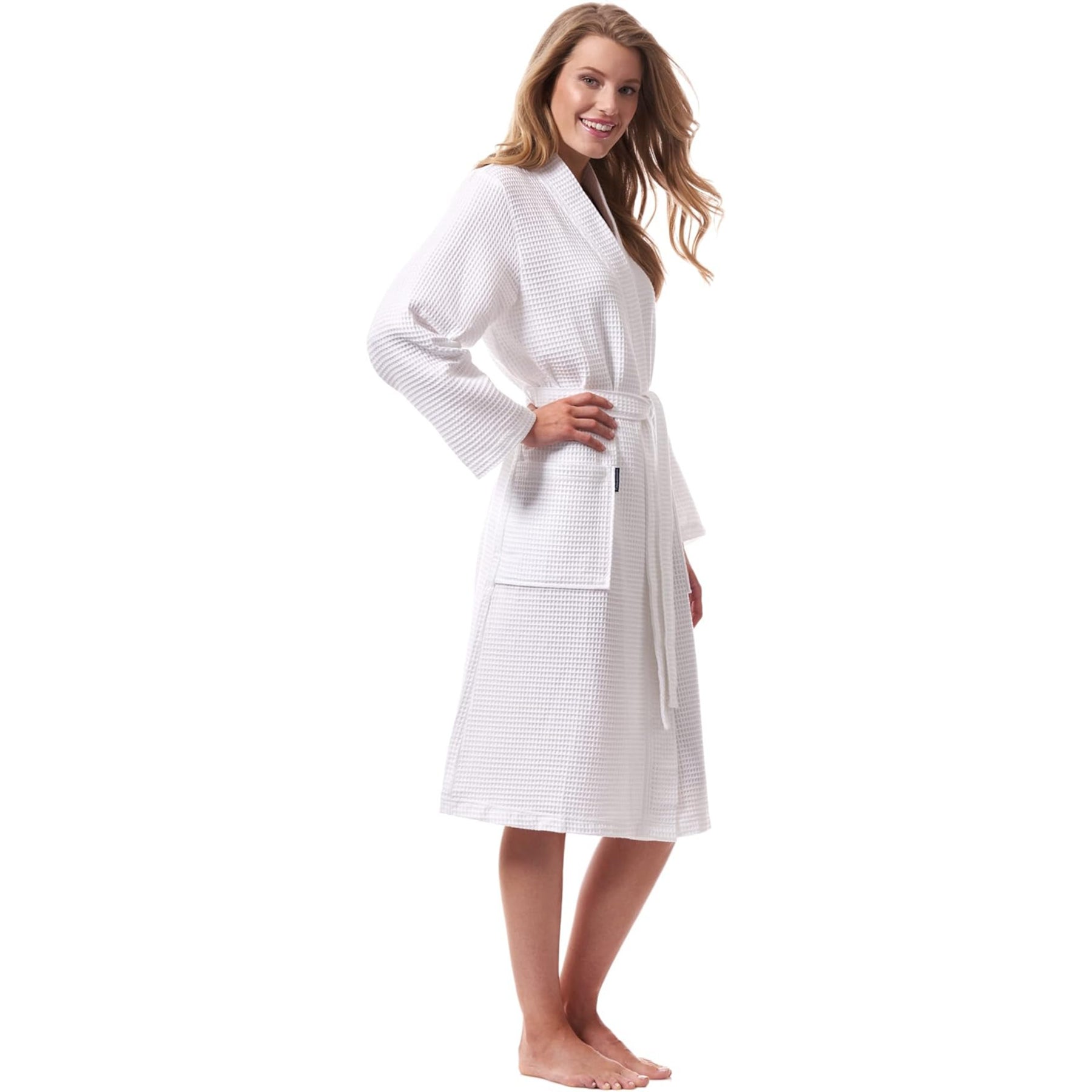Woman in white waffle robe with belt and pockets – relaxed, mid-calf length cotton spa robe.