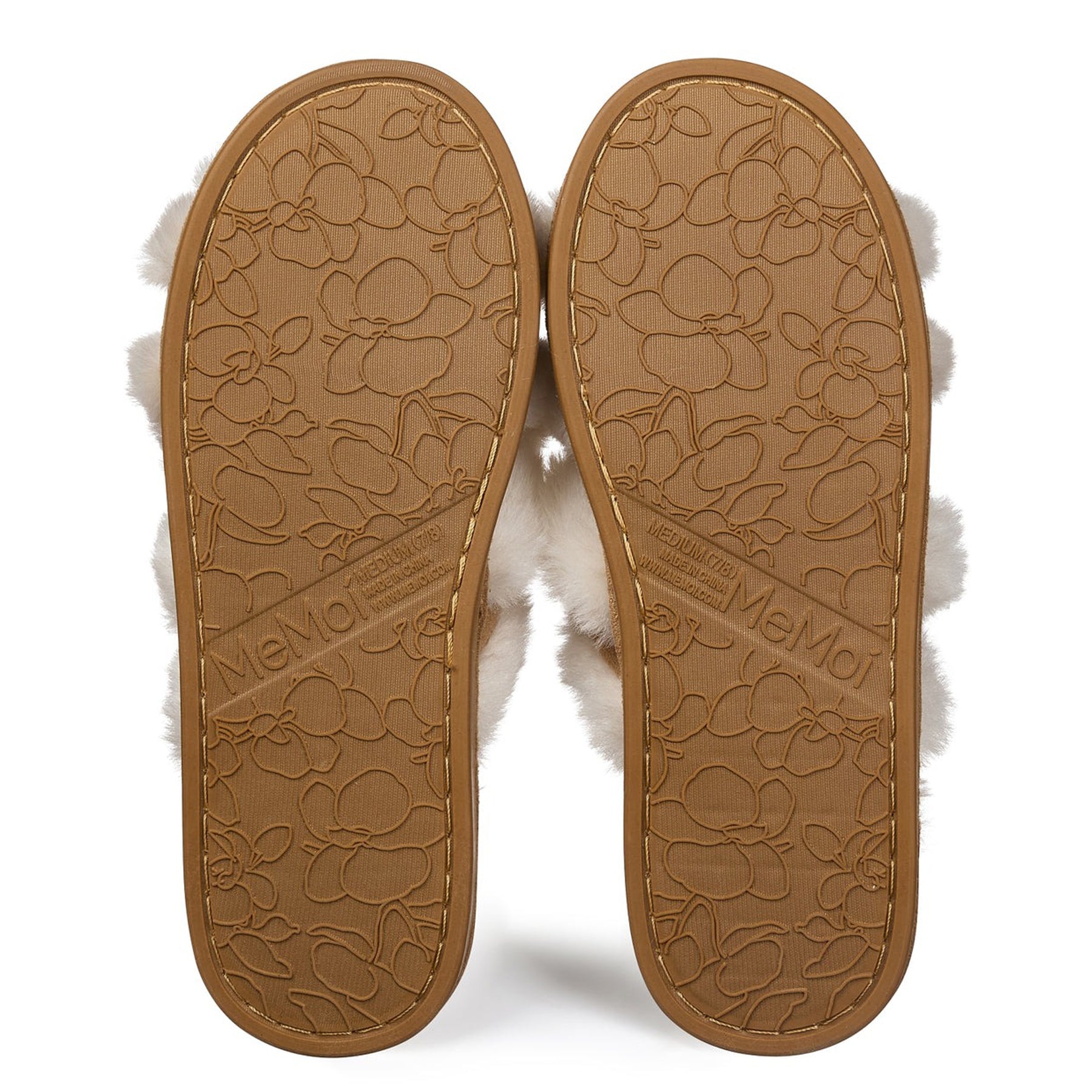 Bottom view of MeMoi ivory faux fur slippers showing tan rubber outsole with floral embossed pattern.