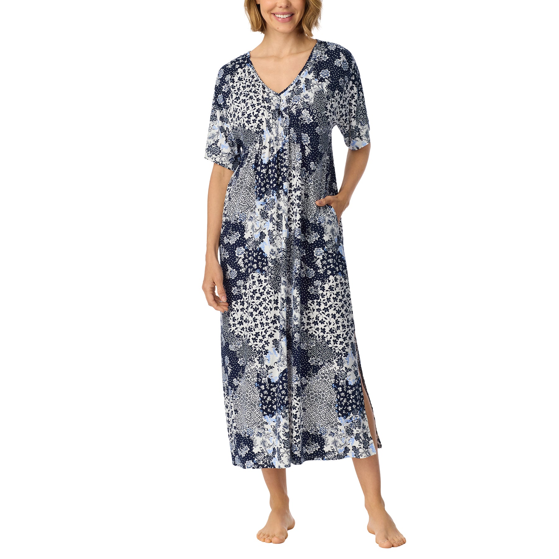 Front view of woman wearing a long navy, white and soft blue patchwork floral nightgown with short sleeves, V-neckline and side pockets.