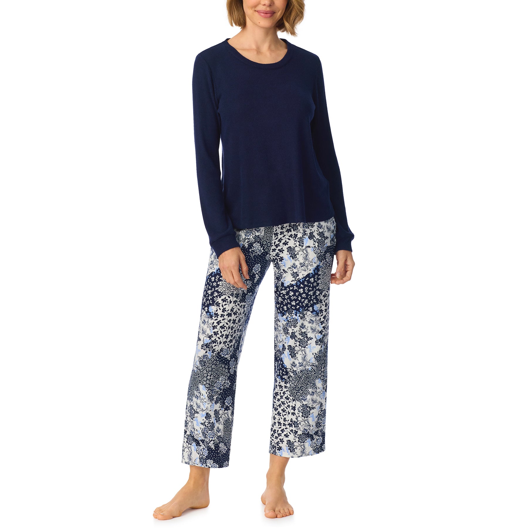 Woman wearing a navy long-sleeve pajama top with cropped blue and white patchwork floral print pants.