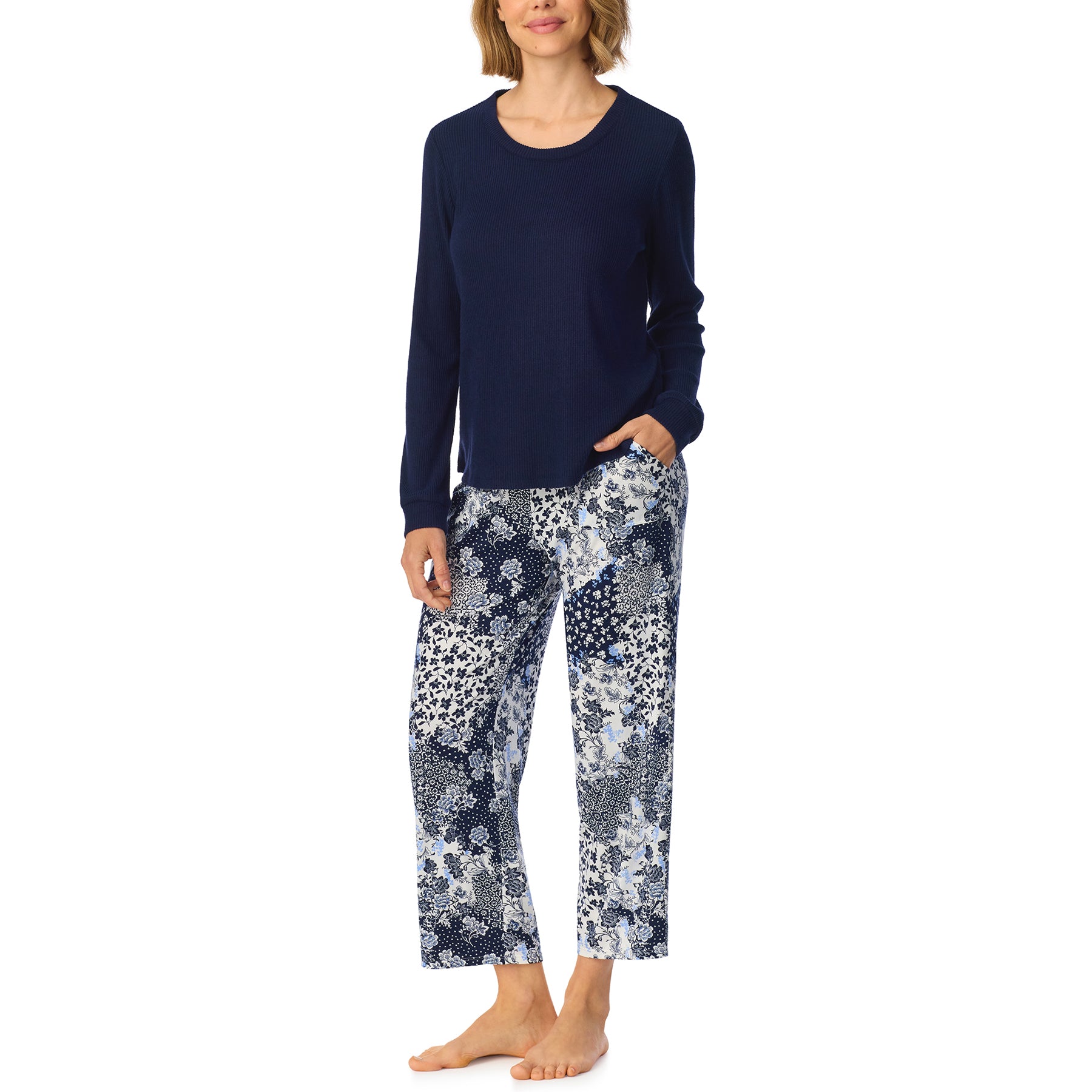 Front view of woman wearing a navy pajama top paired with cropped floral patchwork pajama pants in blue, navy and white.