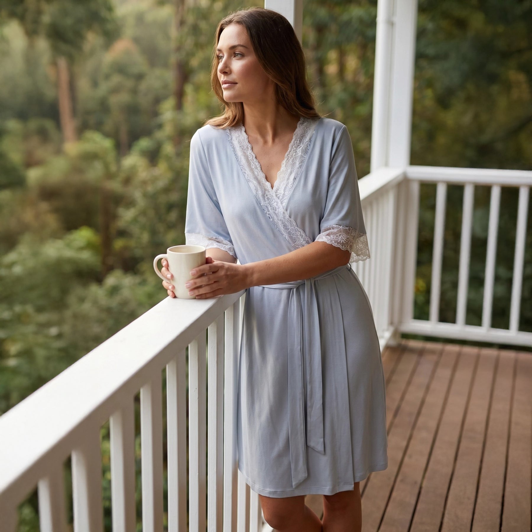 Woman wearing a light blue lace-trim robe with a matching tie belt, styled on a balcony with a soft and elegant sleepwear look.