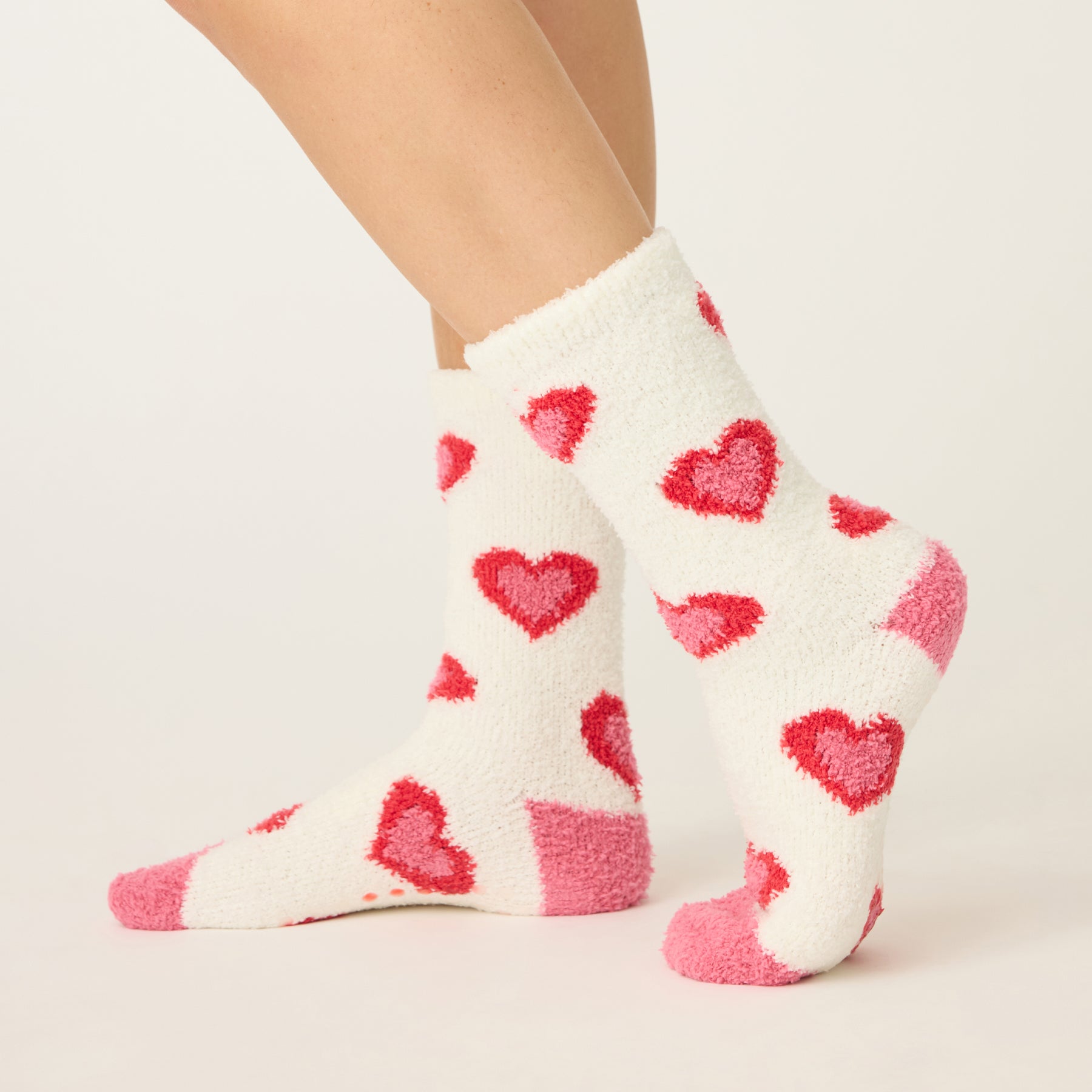 White socks with red heart patterns worn by a person on a light background