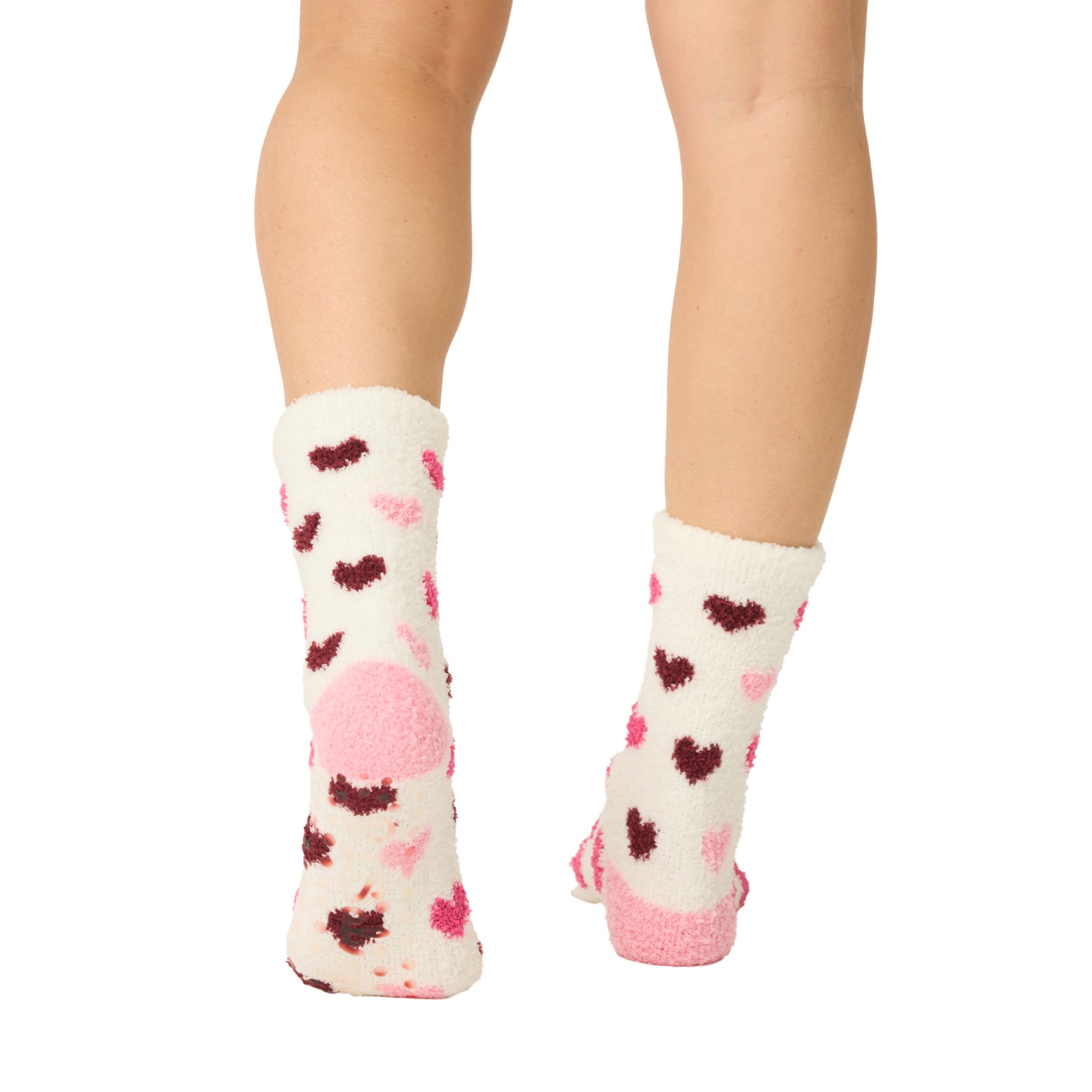 White socks with pink and red heart patterns worn by a person on a white background