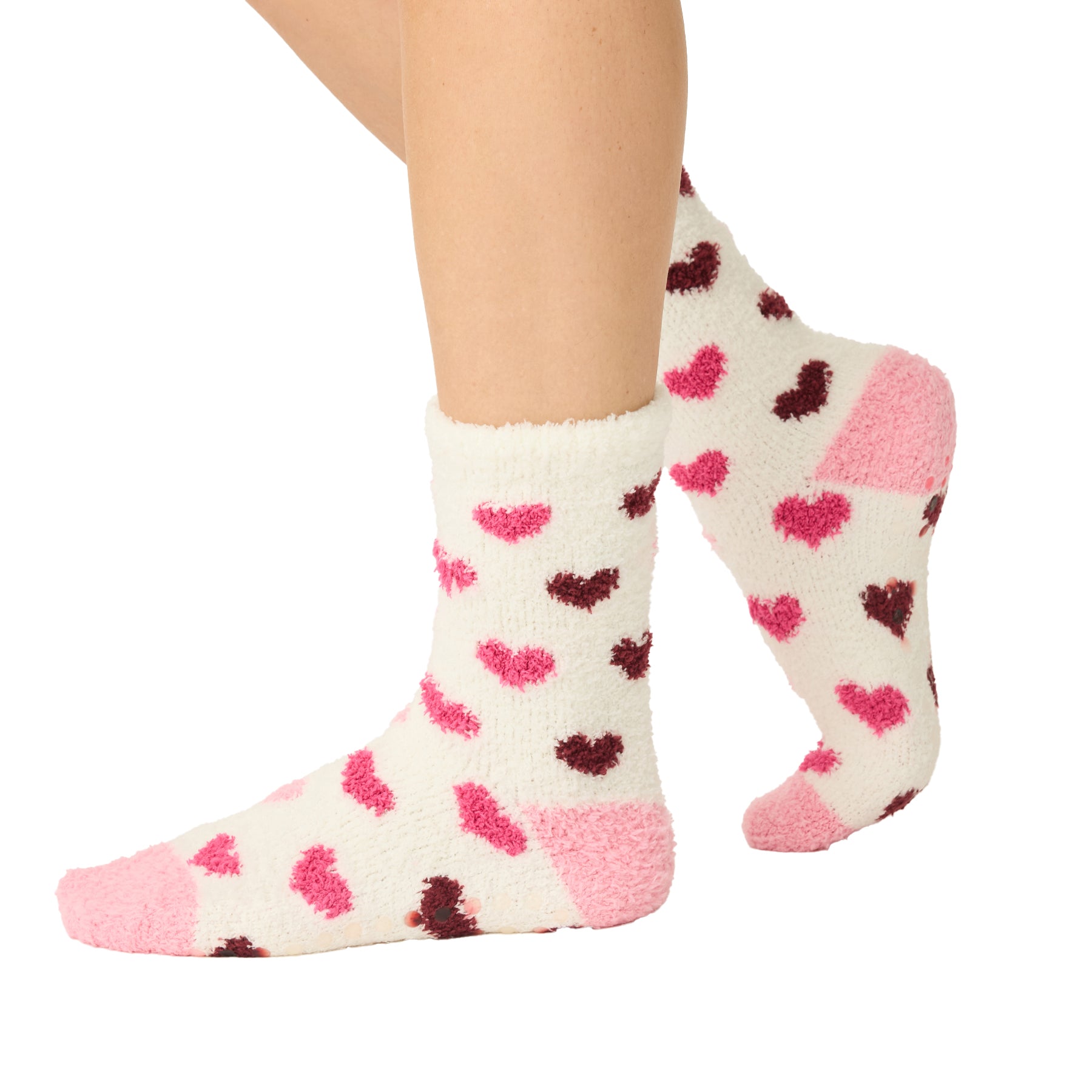 White socks with pink and red heart patterns worn by a person on a white background