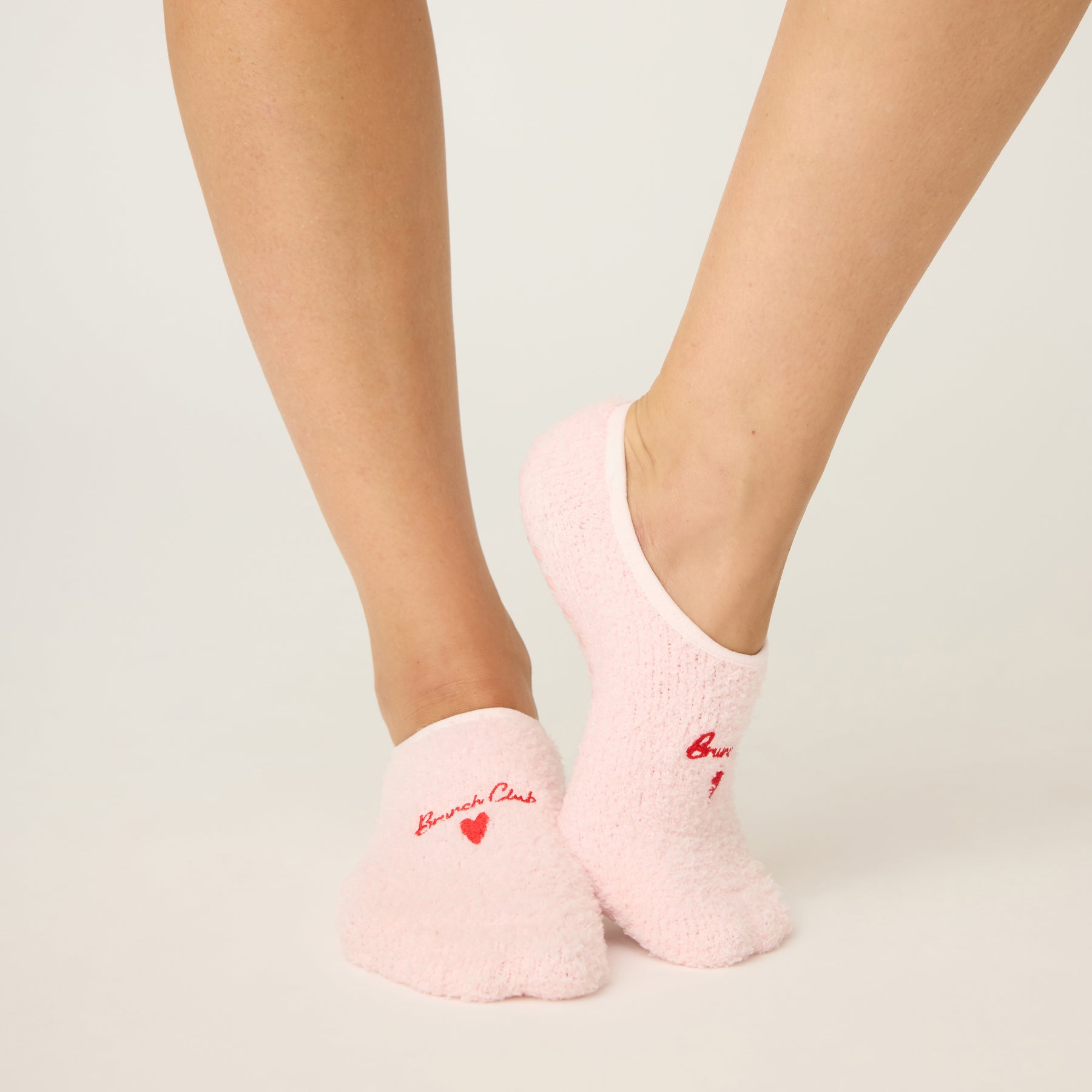 Pink socks with text worn by a person on a light gray background