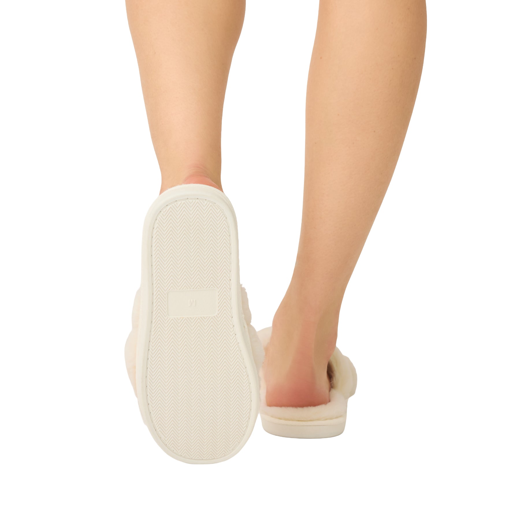 Sole view of ivory faux fur slippers showing the textured non-slip outsole.