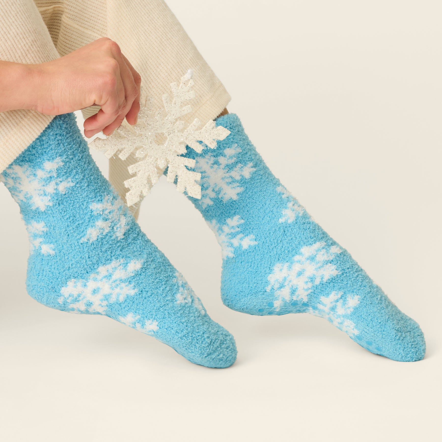 Blue fuzzy crew socks with white snowflake pattern, styled with cozy cream loungewear.