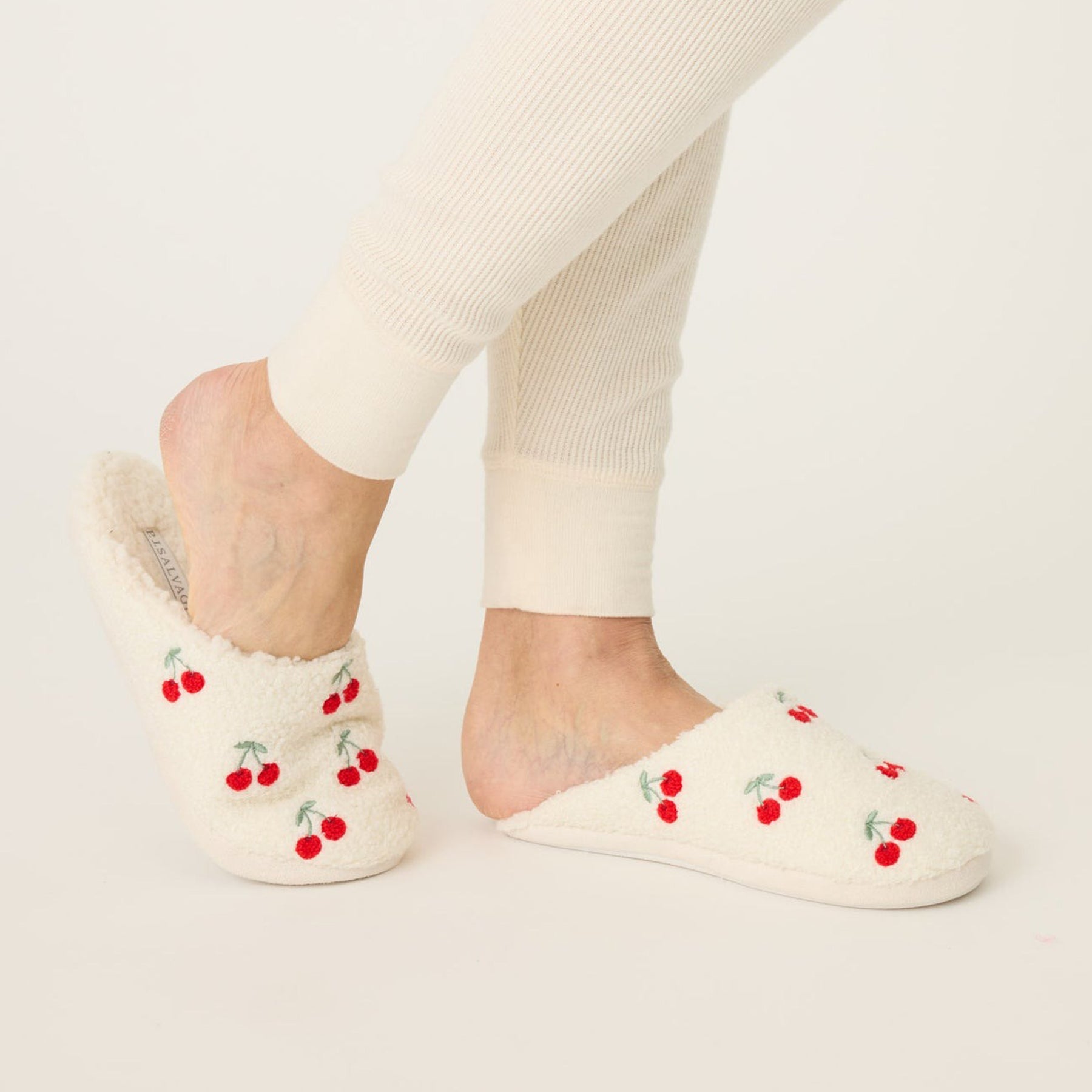 Fuzzy and fleecy slippers in ivory with red cherry print, side view.