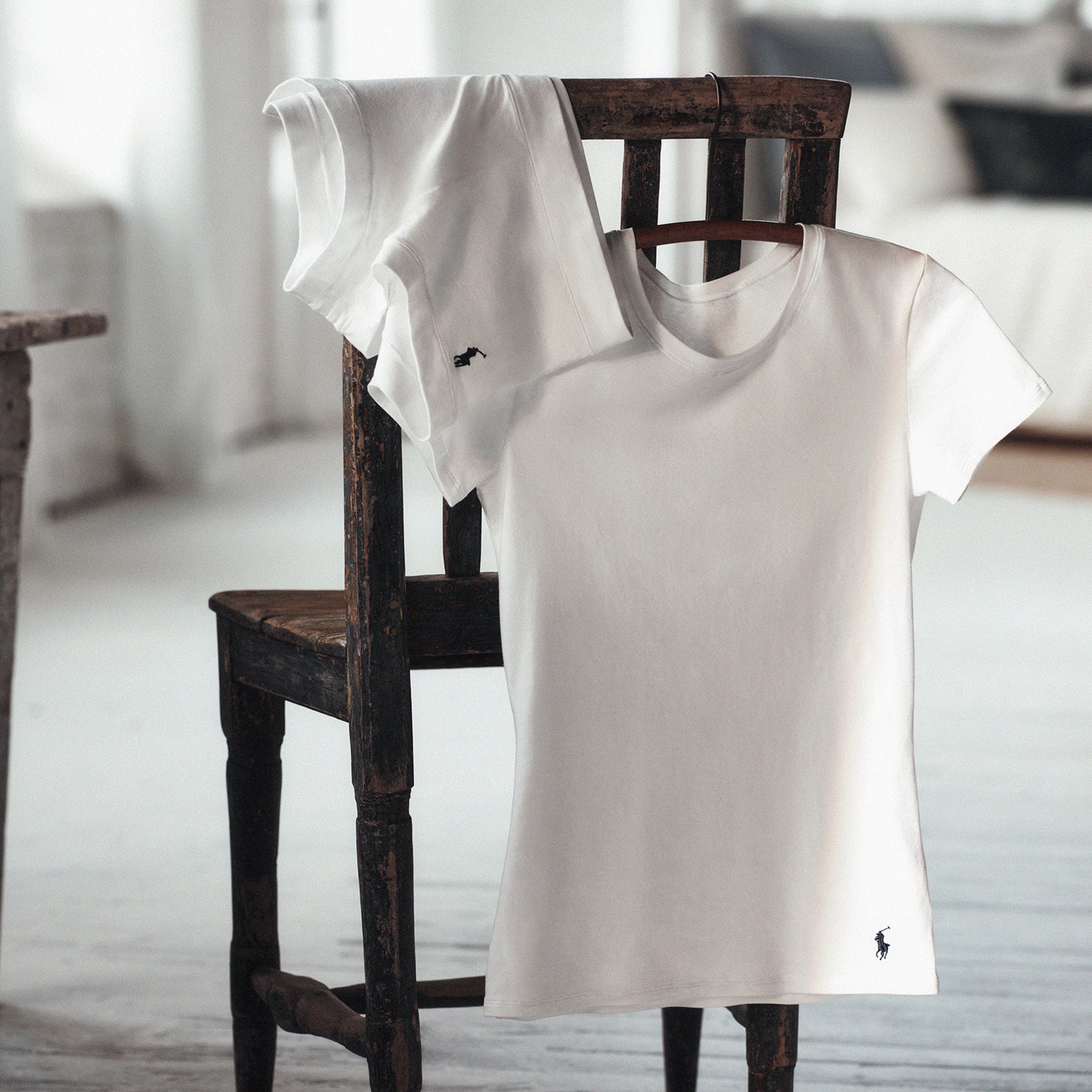 Polo Ralph Lauren white women's t-shirt displayed on wooden chair with logo detail visible