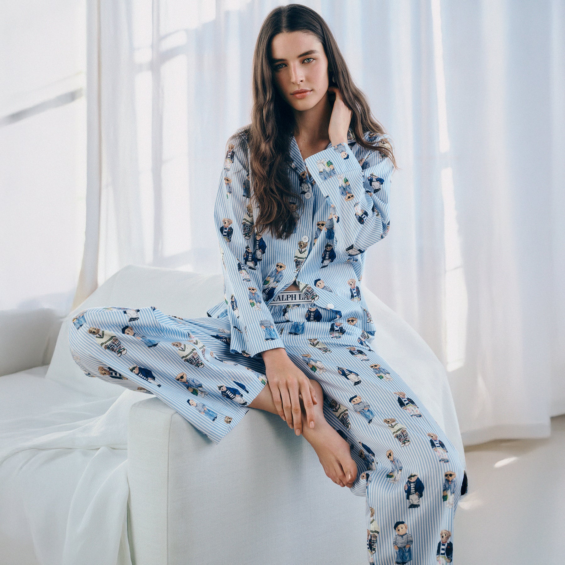 Polo Ralph Lauren women's pyjama set with oxford stripe and Polo Bear print, lifestyle image on model sitting