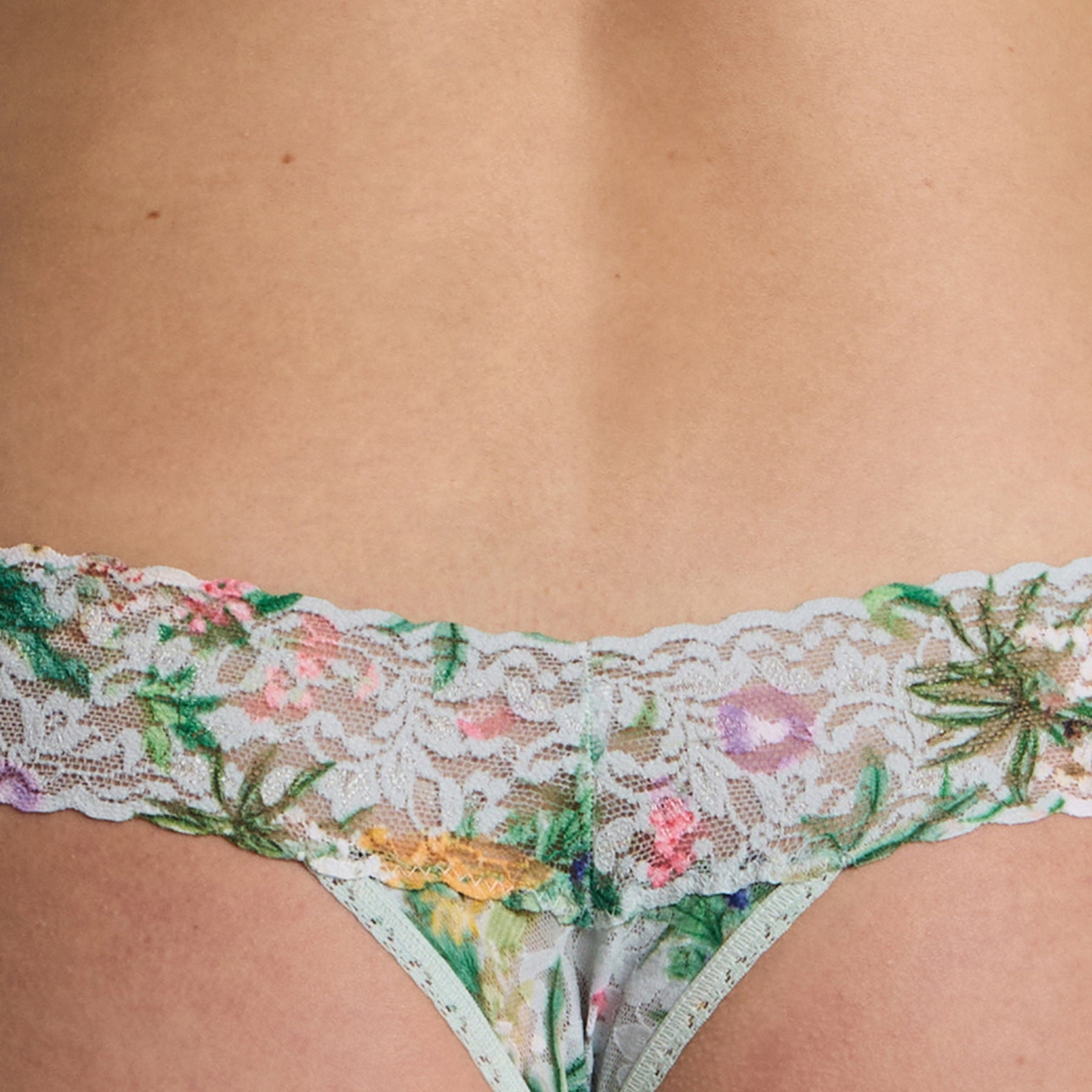 Close-up front detail of the floral lace thong showing the scalloped waistband and fine lace texture.
