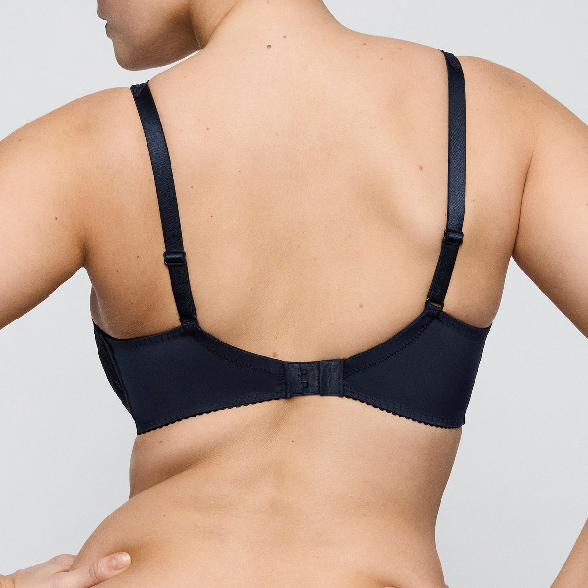 PrimaDonna 0262127 Madison seamless full cup underwired bra without lining. Sheer, embroidered lace cups in navy velvet blue. Rear view on model. 