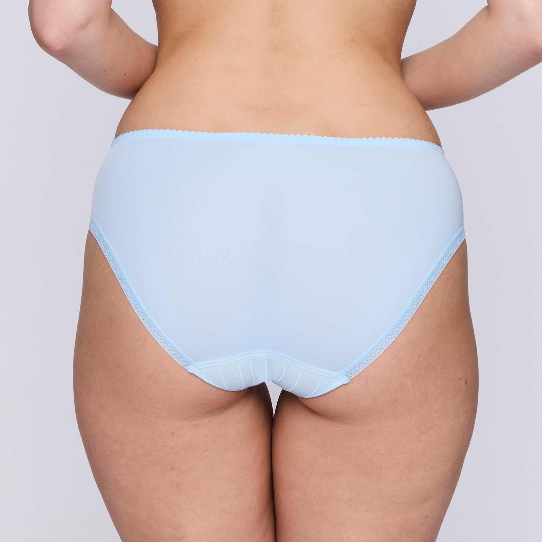 Mid-rise brief in milky baby blue with contrast lime green embroidery on front panel. Rear view on model.