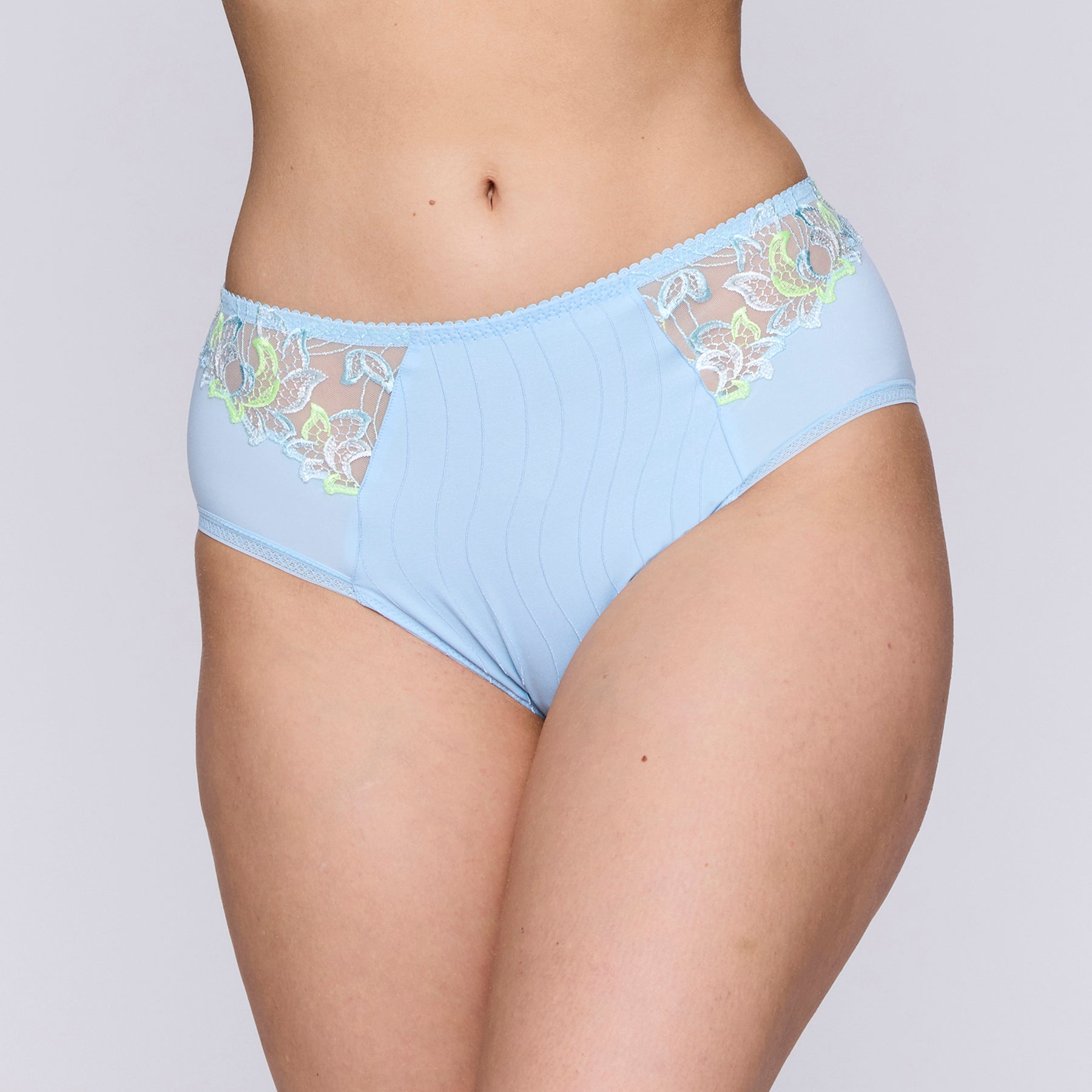 Full brief in milky baby blue with contrast lime green embroidery at hips. Front view on model.