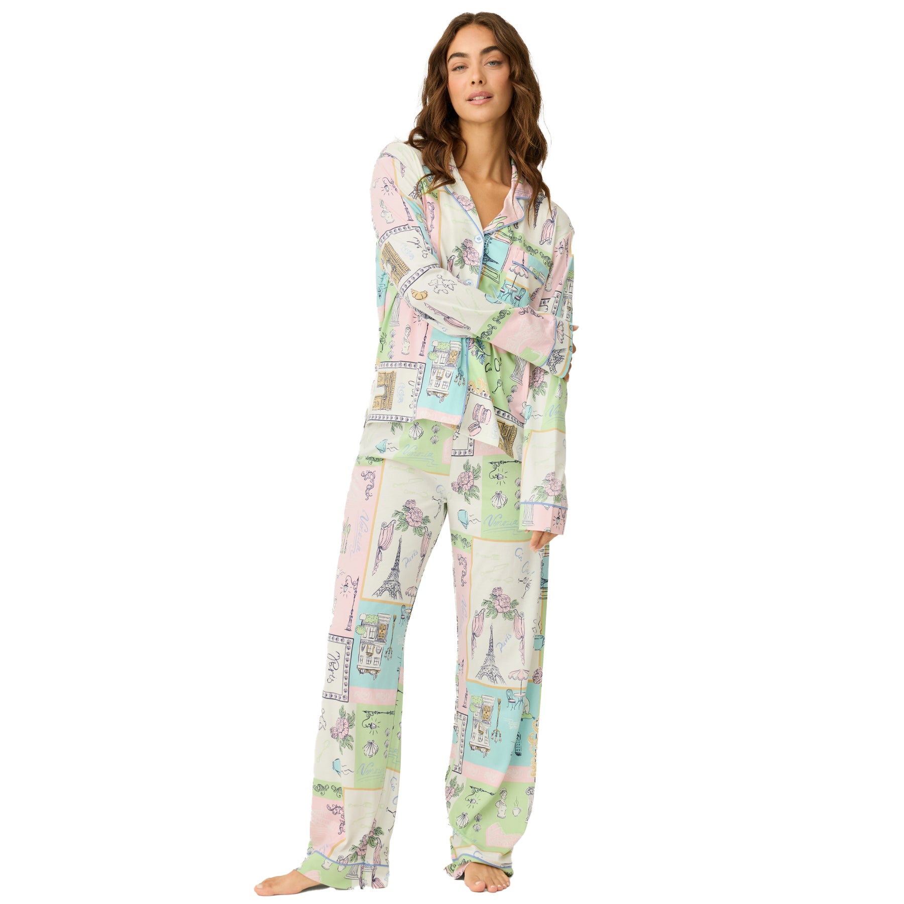 Women’s long sleeve pyjama set with button-up top and full-length pants in a pastel travel-inspired print, front view on a white background.