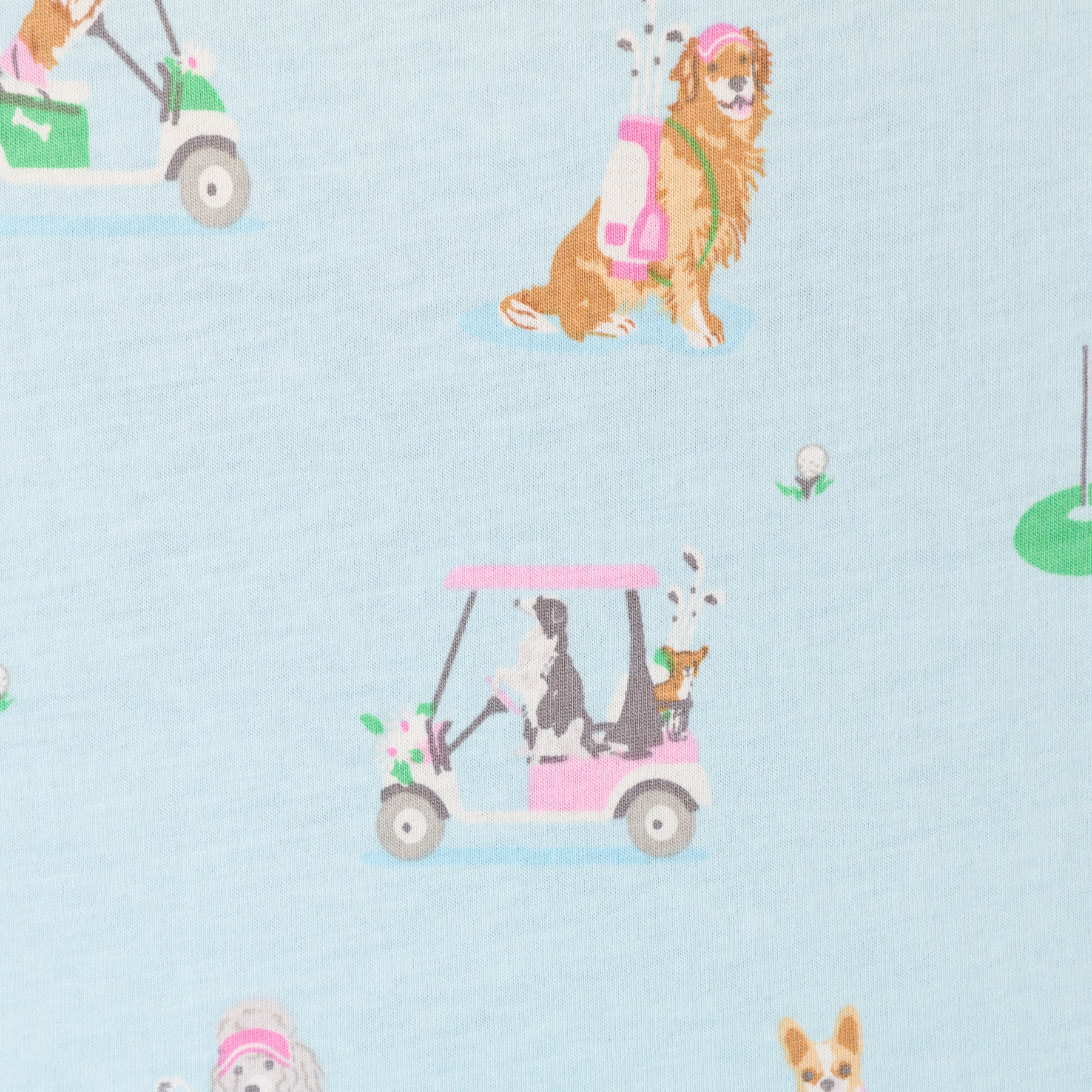 Close-up of light blue pyjama fabric featuring dogs, golf carts, and golf-themed print