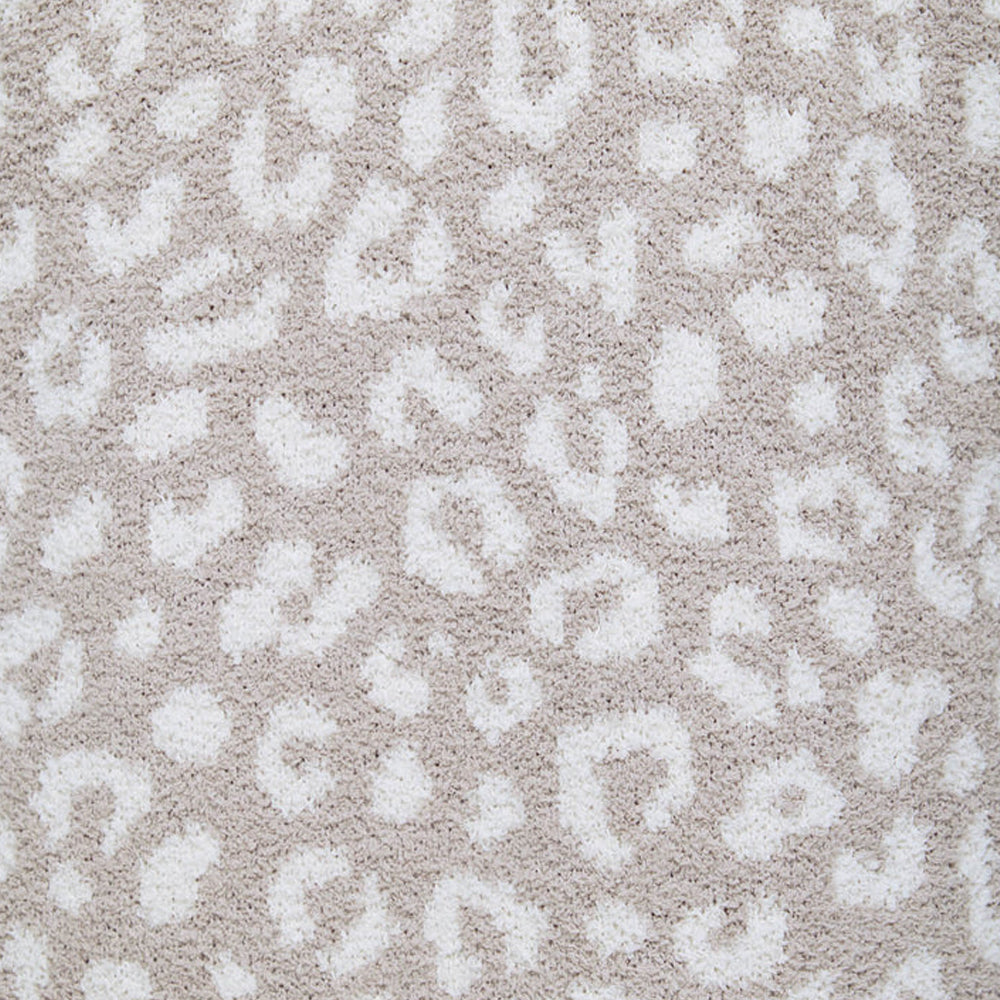 Close-up of soft beige knit fabric featuring an all-over ivory leopard print with a plush, textured finish.