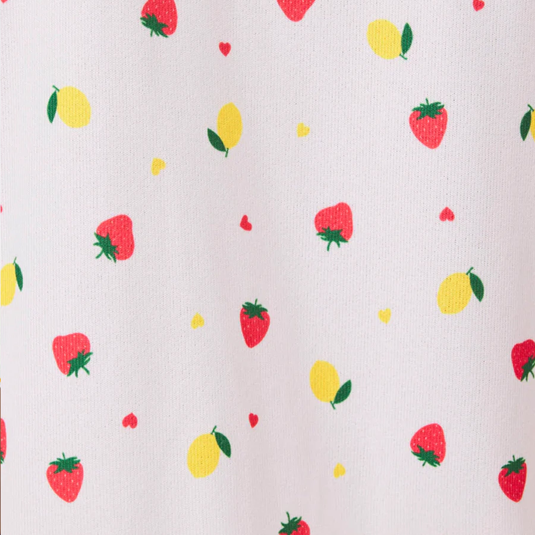 Close-up of white fabric with scattered strawberry and lemon print and small heart accents