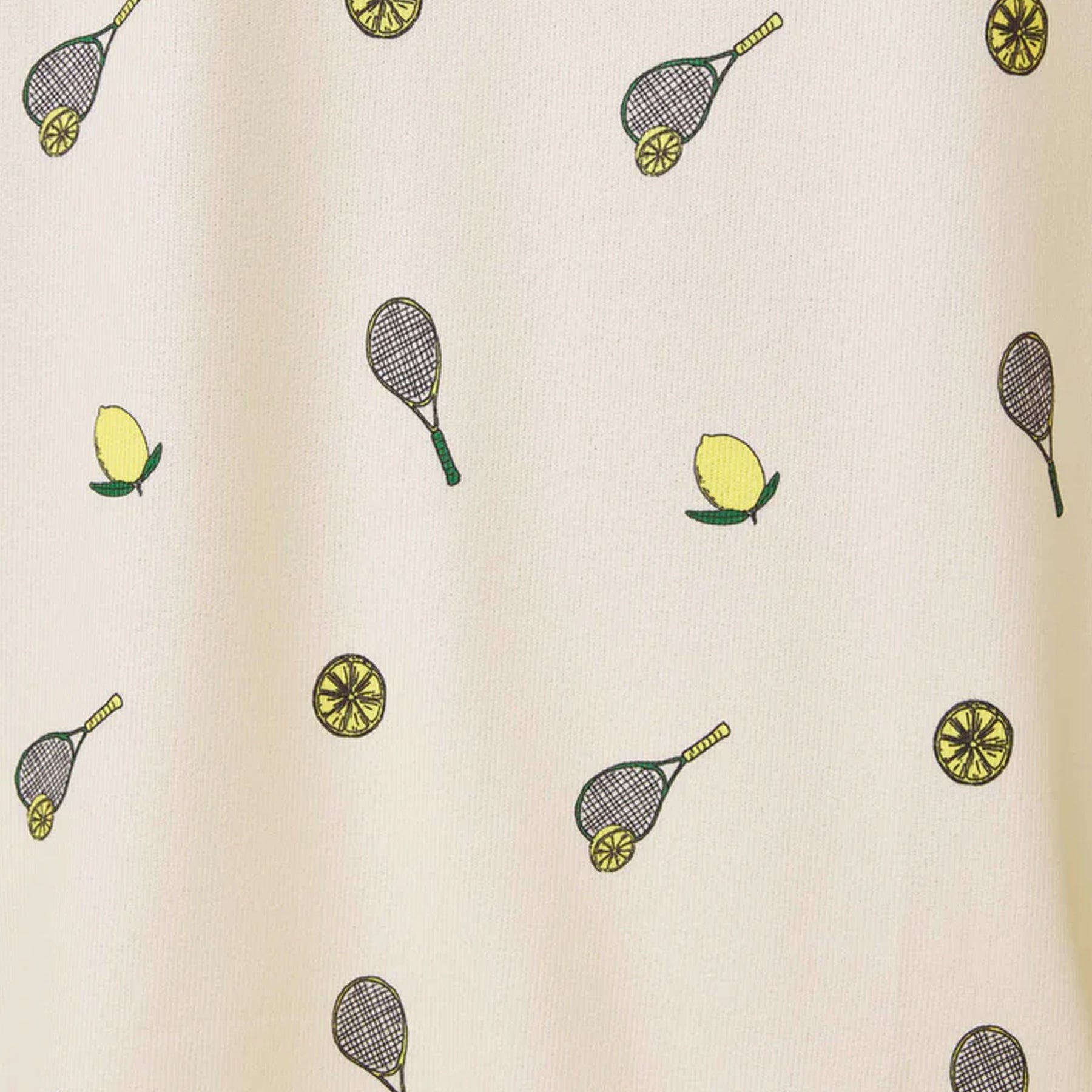 Close-up of soft yellow fabric with scattered lemon slices and tennis racket print