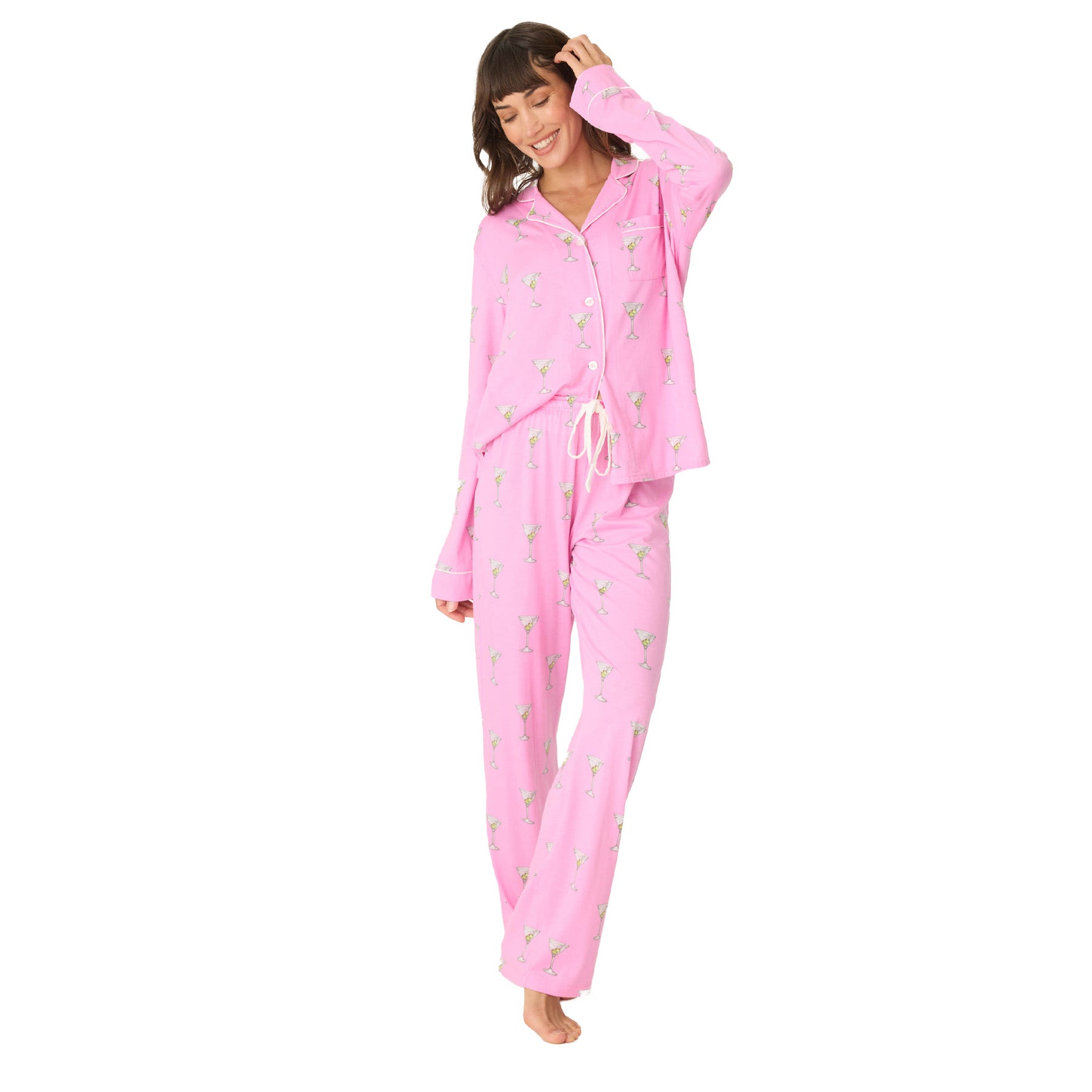 A woman standing and smiling in a pink martini-print pajama set, with a relaxed fit and white drawstring waist.