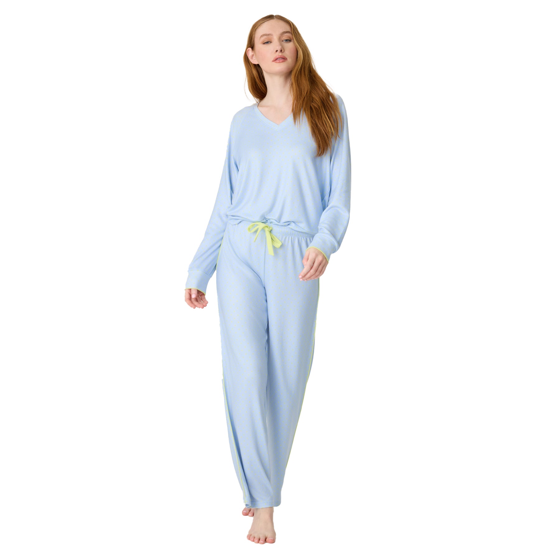 Full view of woman in light blue pajama set with long-sleeve top and drawstring pants, yellow tie at waist.