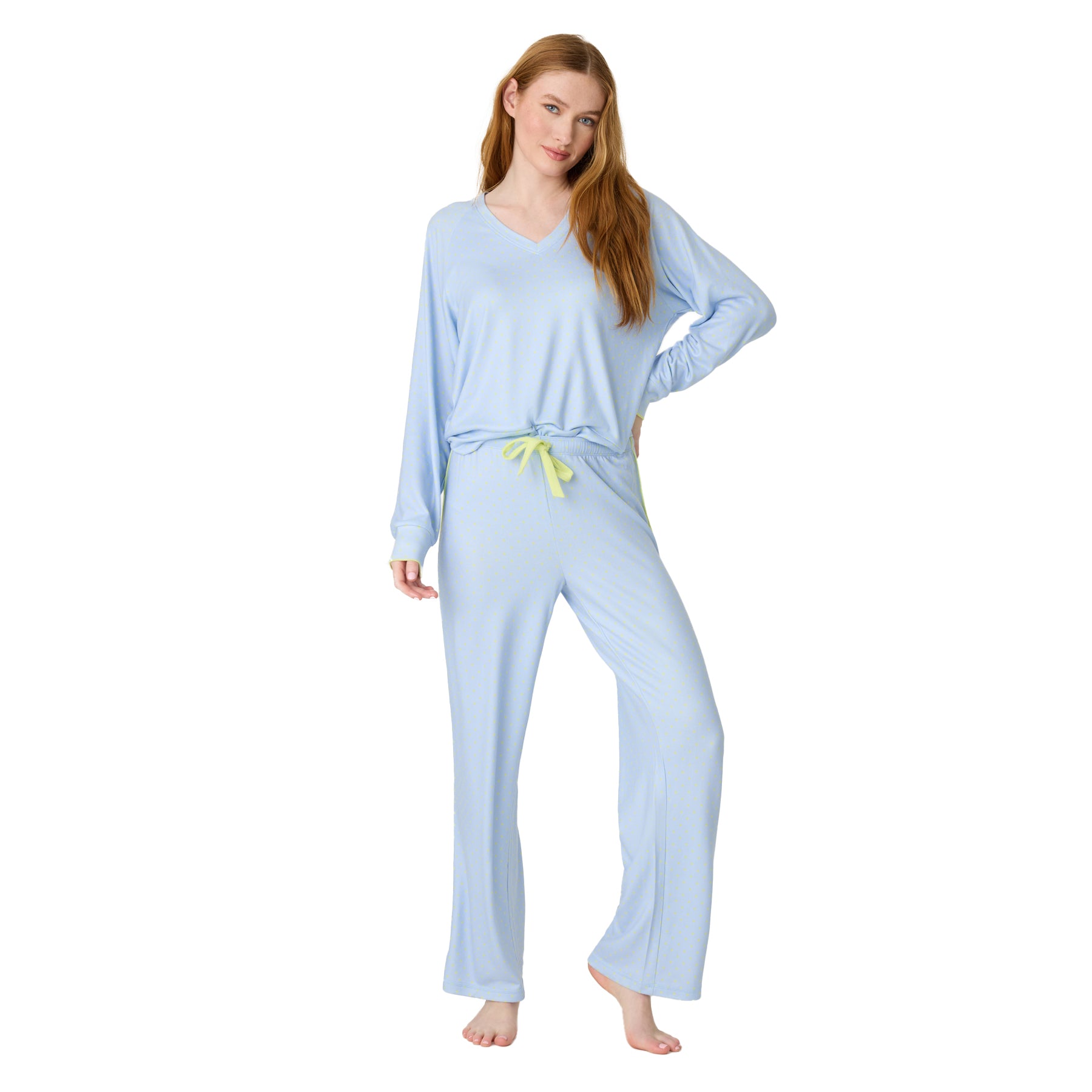 Woman posing in light blue pajama set with V-neck long-sleeve top and wide-leg pants, yellow drawstring accent.