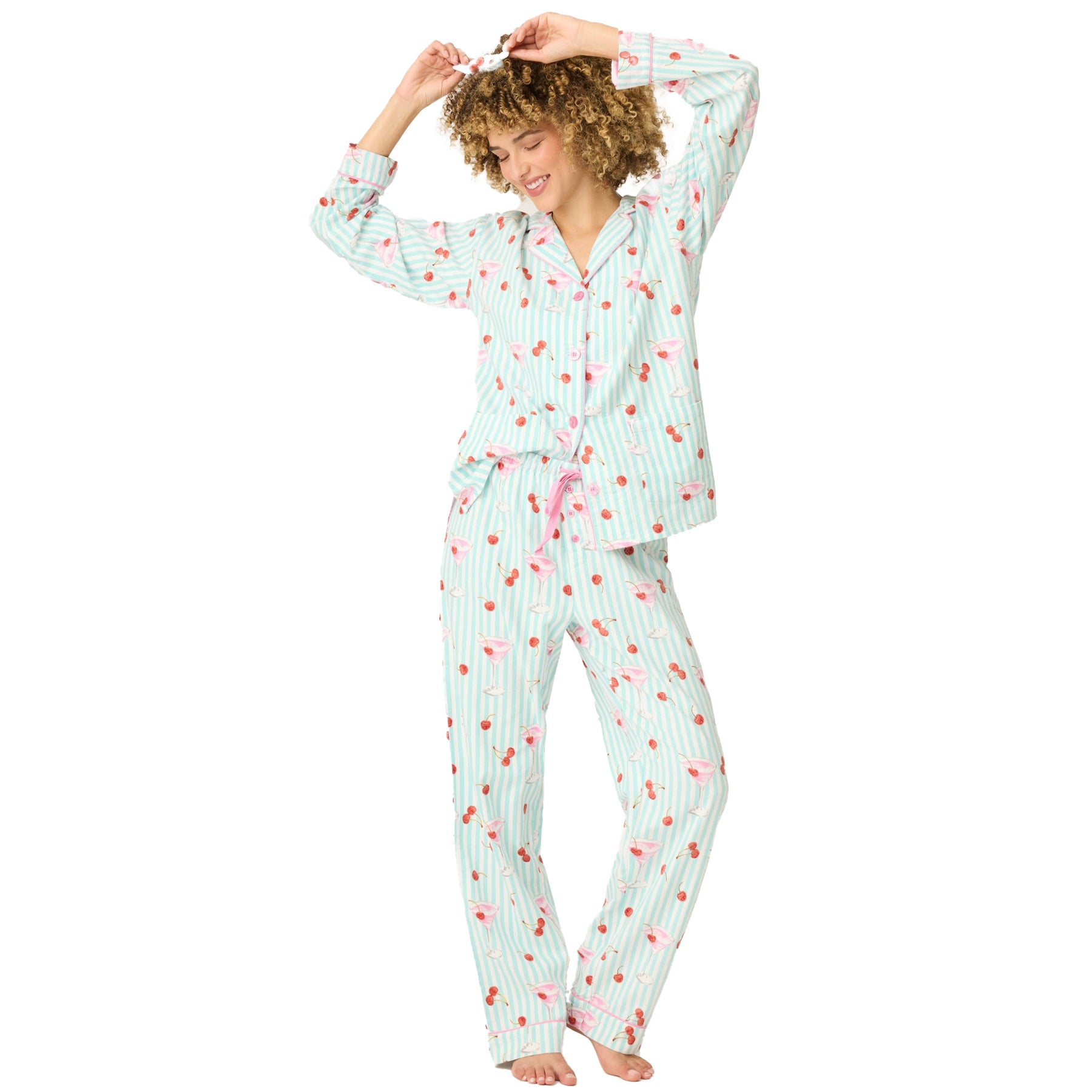 Woman wearing a light blue pajama set with red cherry pattern on a white background