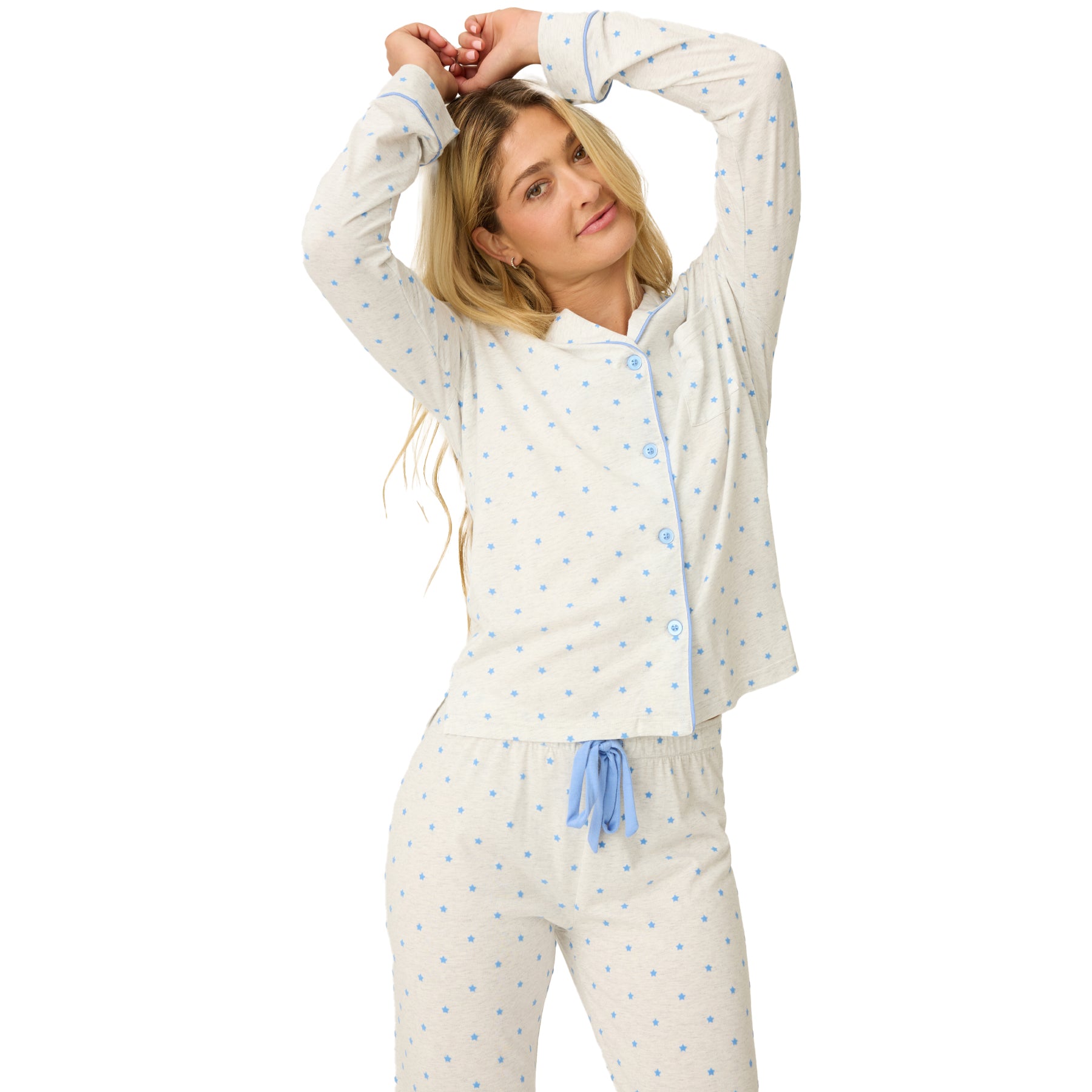 Woman wearing a white pajama set with blue polka dots on a white background
