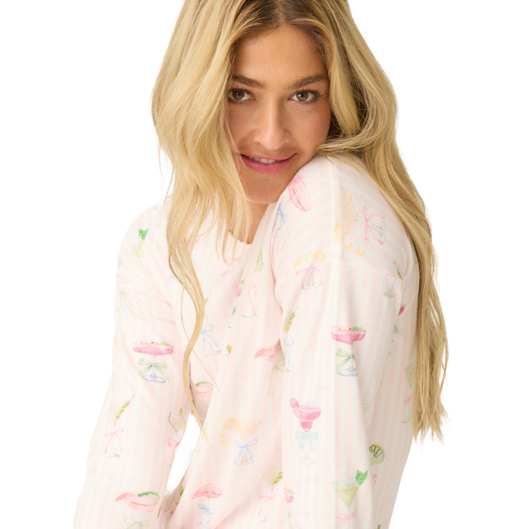Woman wearing long sleeve pyjama top in light pink with pastel cocktail glass print.