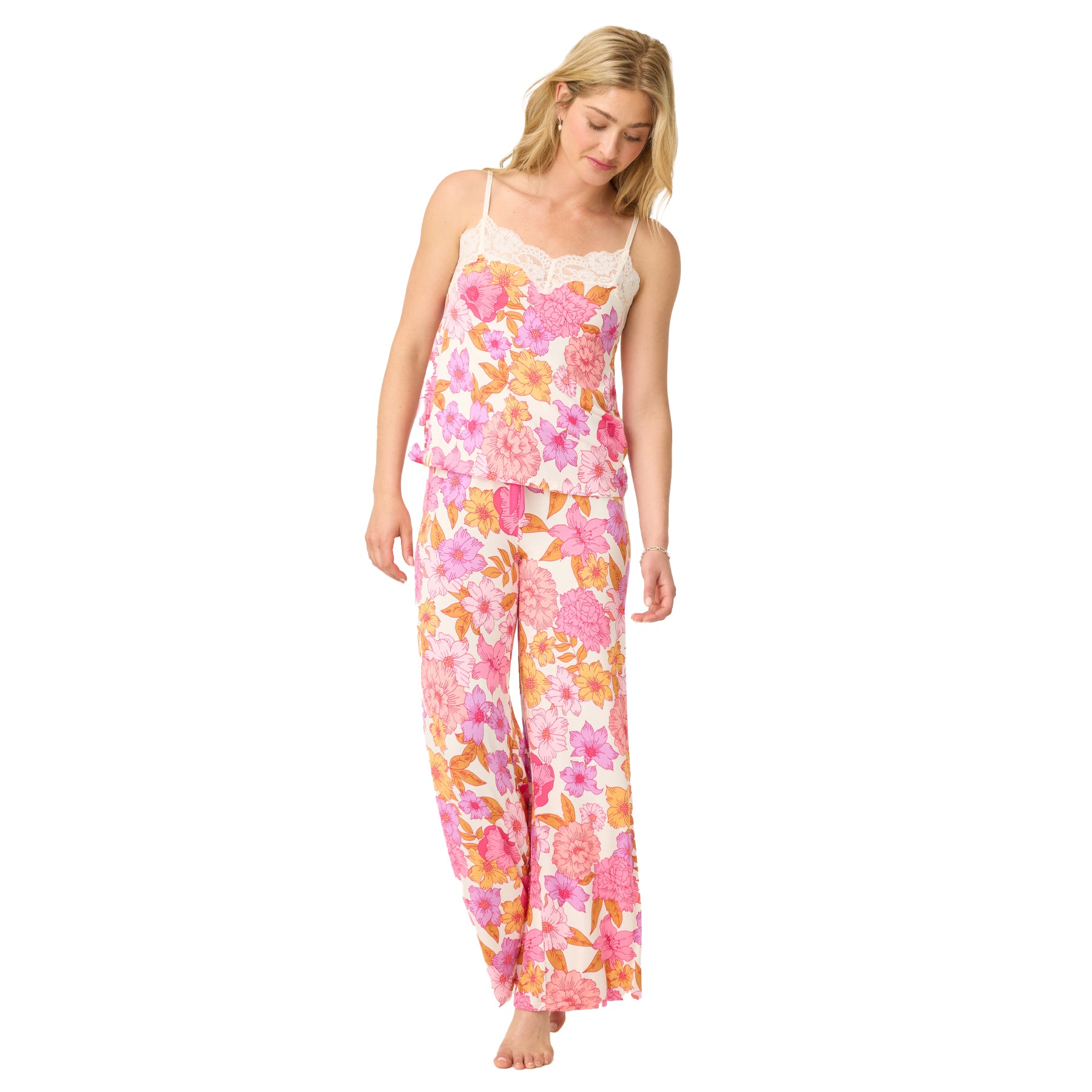 Model walking barefoot in a coordinated floral sleepwear set with a lace-trim camisole and wide-leg pants in bold pink, orange, and purple flower prints.
