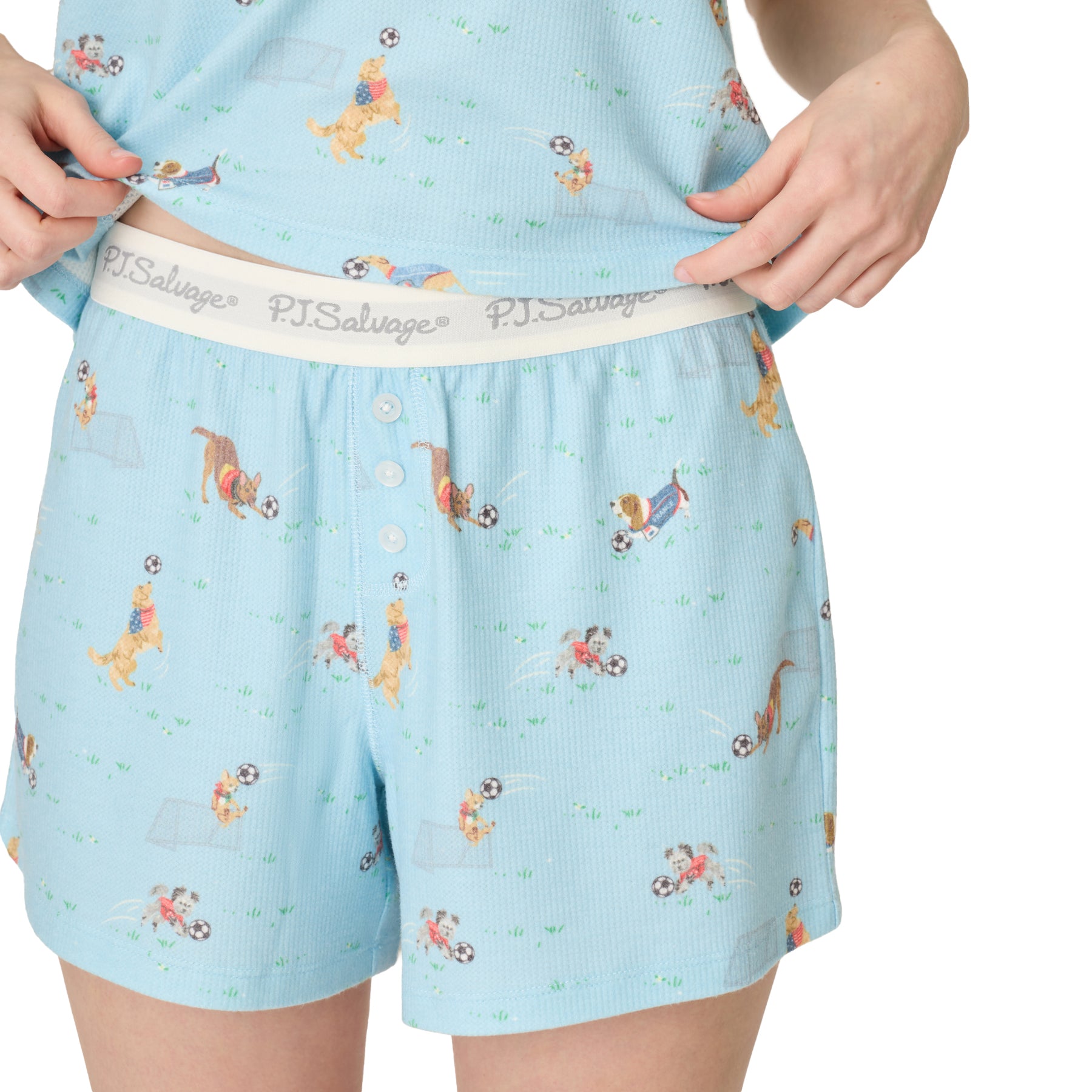 Close-up of PJ Salvage pajama shorts with elastic logo waistband and button detail, blue dog print fabric