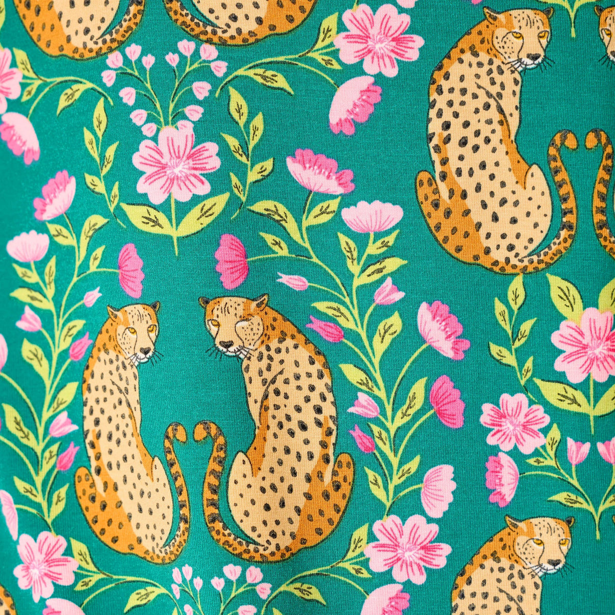 Close-up of teal fabric featuring paired golden cheetahs surrounded by bright pink flowers and green foliage.