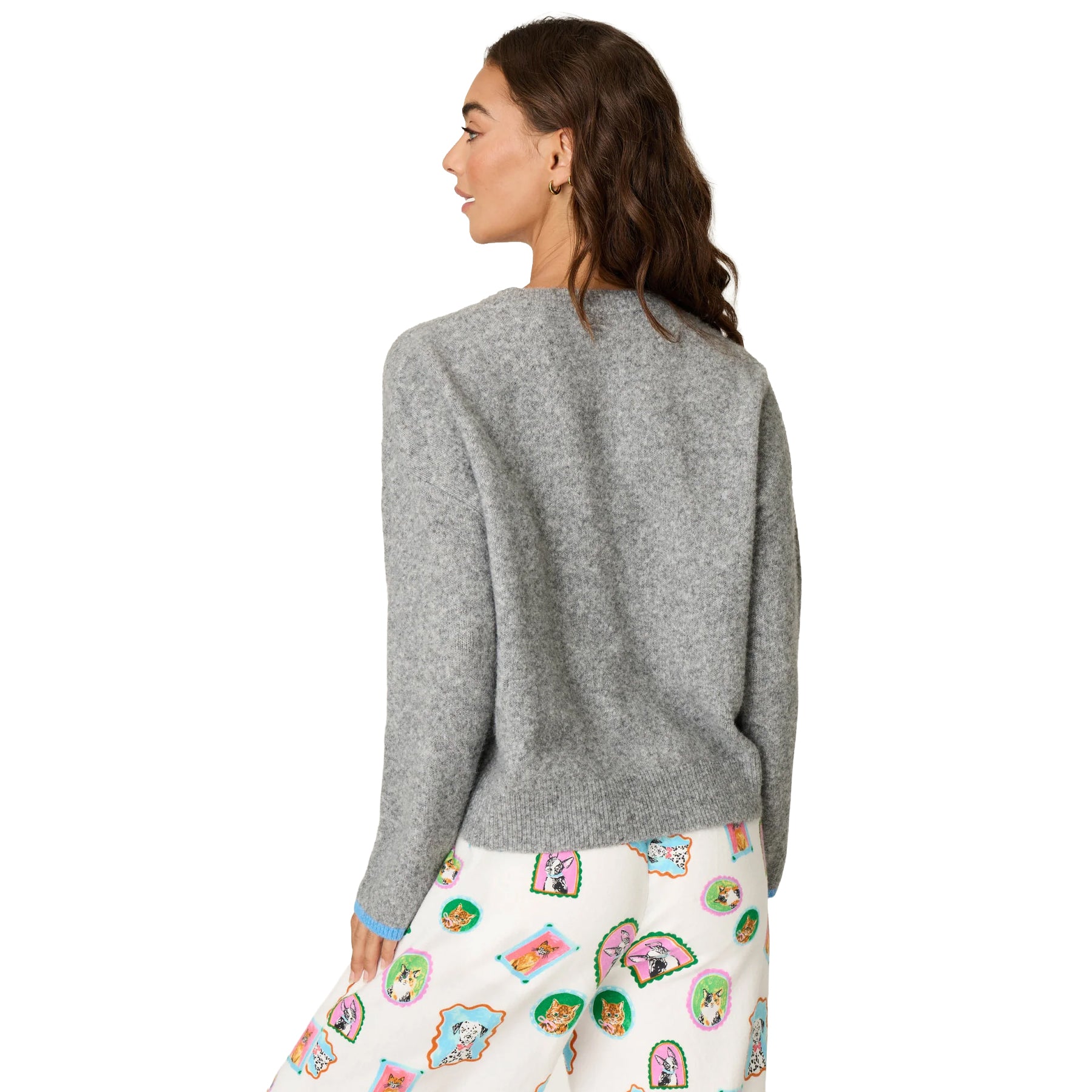 A woman shown from the back wearing a heather gray knit cardigan and white pants with a colorful patchwork print, against a plain white background.