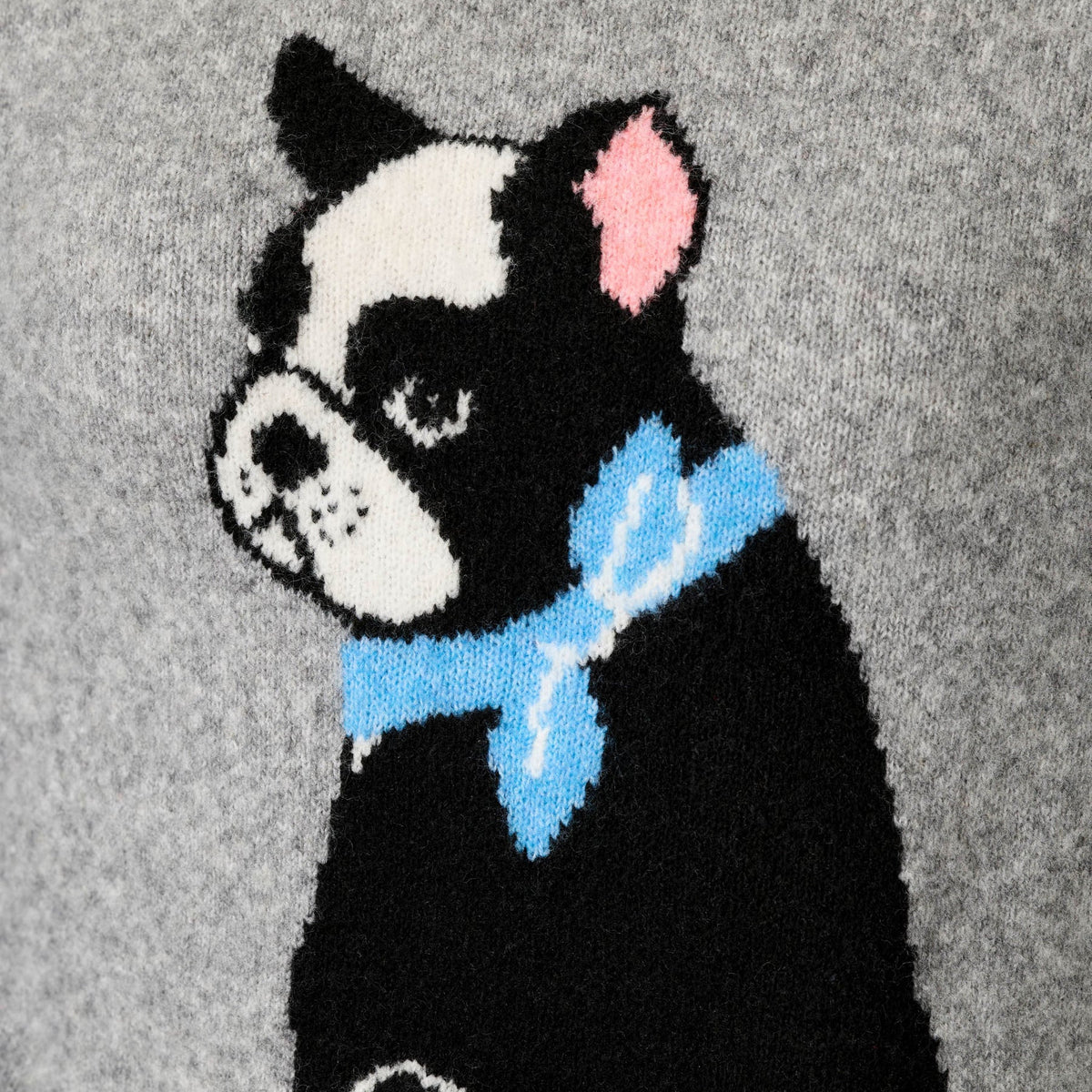 Close-up of a knitted sweater featuring a black and white Boston Terrier dog wearing a light blue bow tie, set against a heather gray background.
