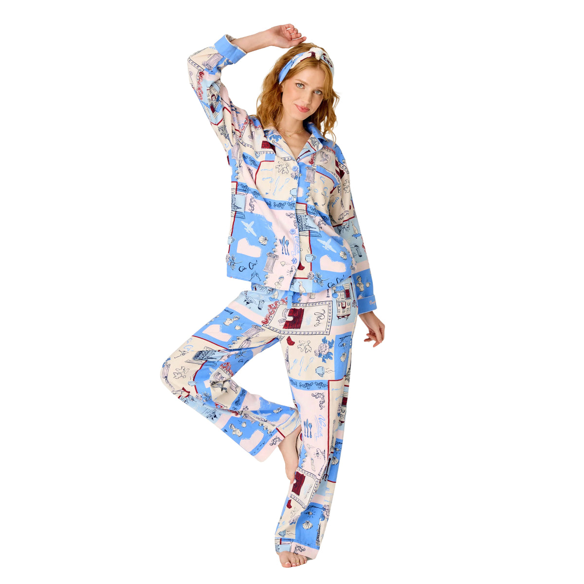Woman wearing a blue, blush and cream Paris-inspired print pajama set with button-up top, relaxed pants and matching headband.