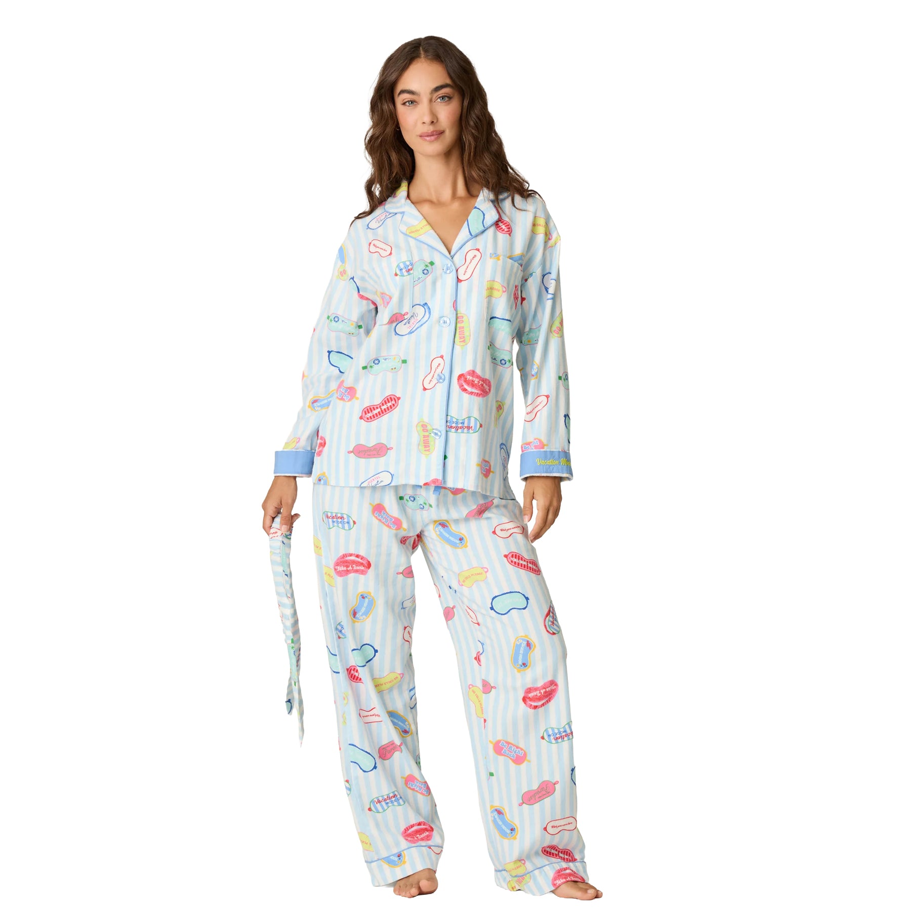 Woman wearing a light blue and white striped pajama set with colourful vacation-themed print, button-up top and relaxed pants.